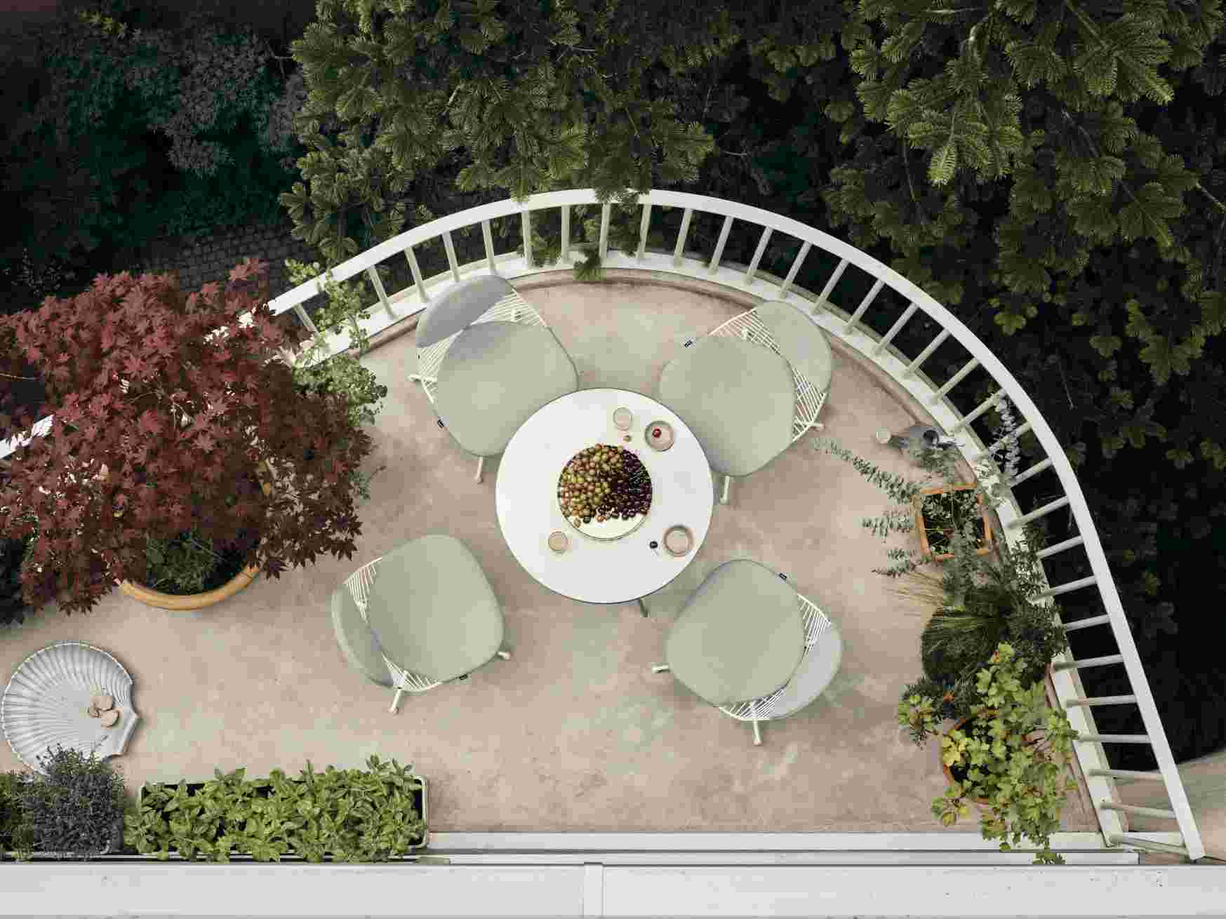 Draufsicht: Vitra Wire Chair Bikini Outdoor Sitzgruppe mit Tisch und Pflanzen auf einer Terrasse.