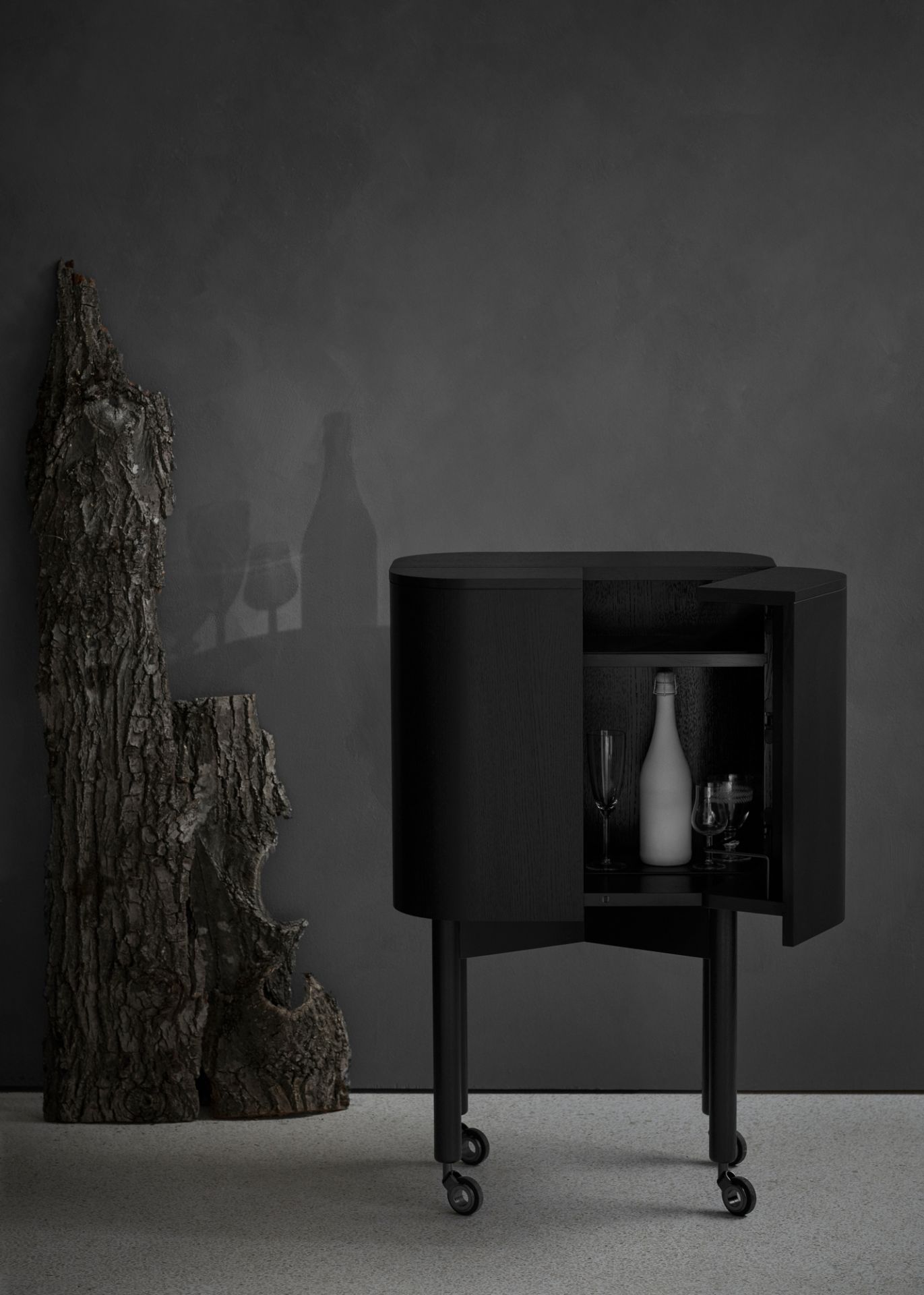Schwarzer Loud Bar Cabinet Barschrank von Northern mit geöffneter Tür, Flasche und Gläsern auf Rollen.