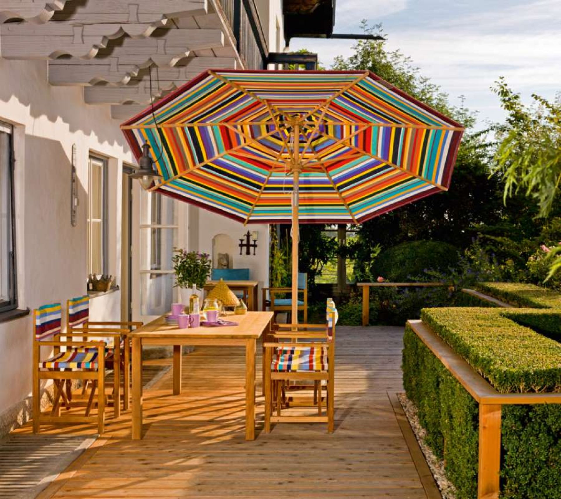 Cabin Sessel von Weishäupl aus Tanne mit farbenfrohen Streifen auf Terrasse mit Gartentisch.