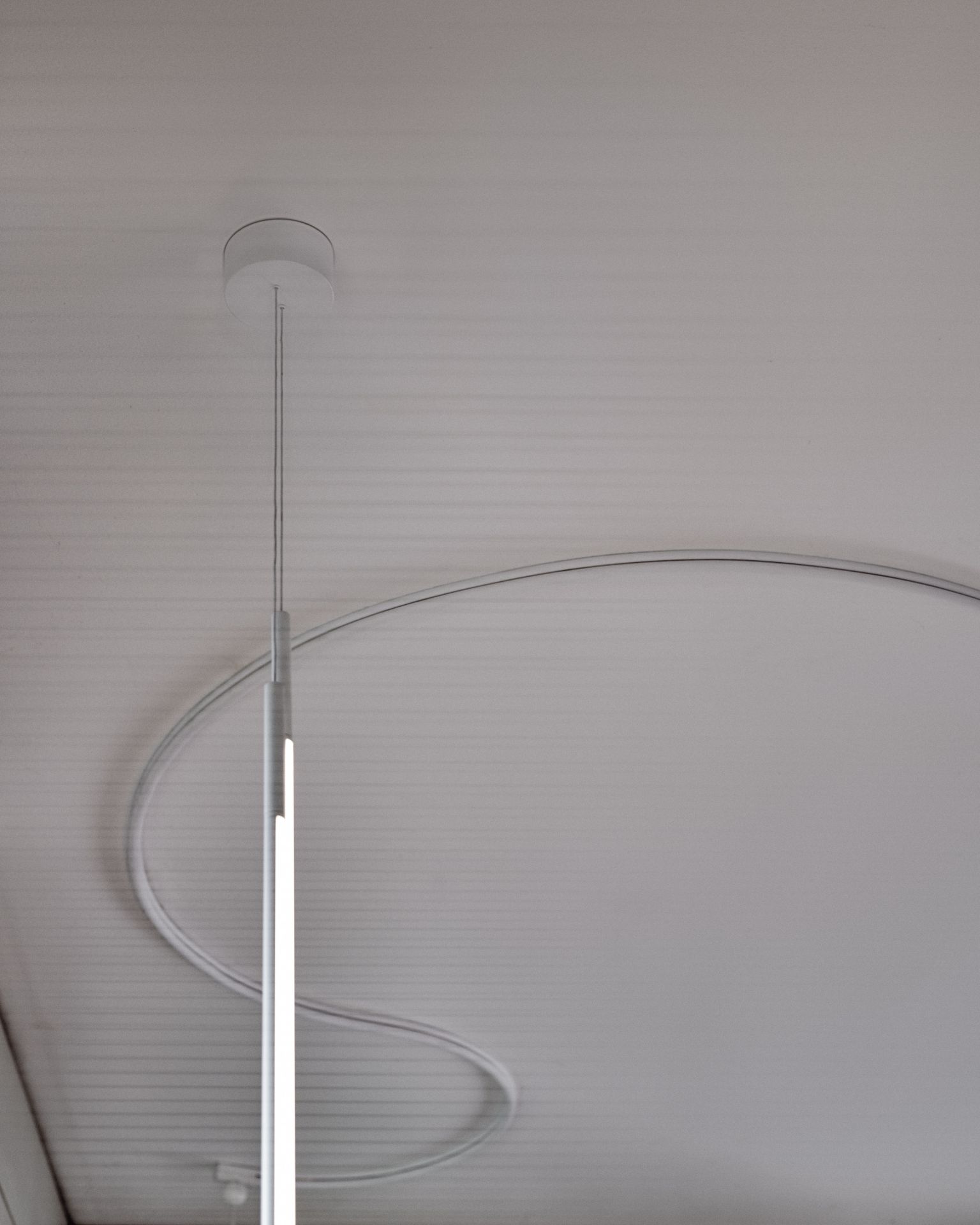 Nahaufnahme der modernen, weißen My Lines Hängeleuchte von Flos an einer Decke.
