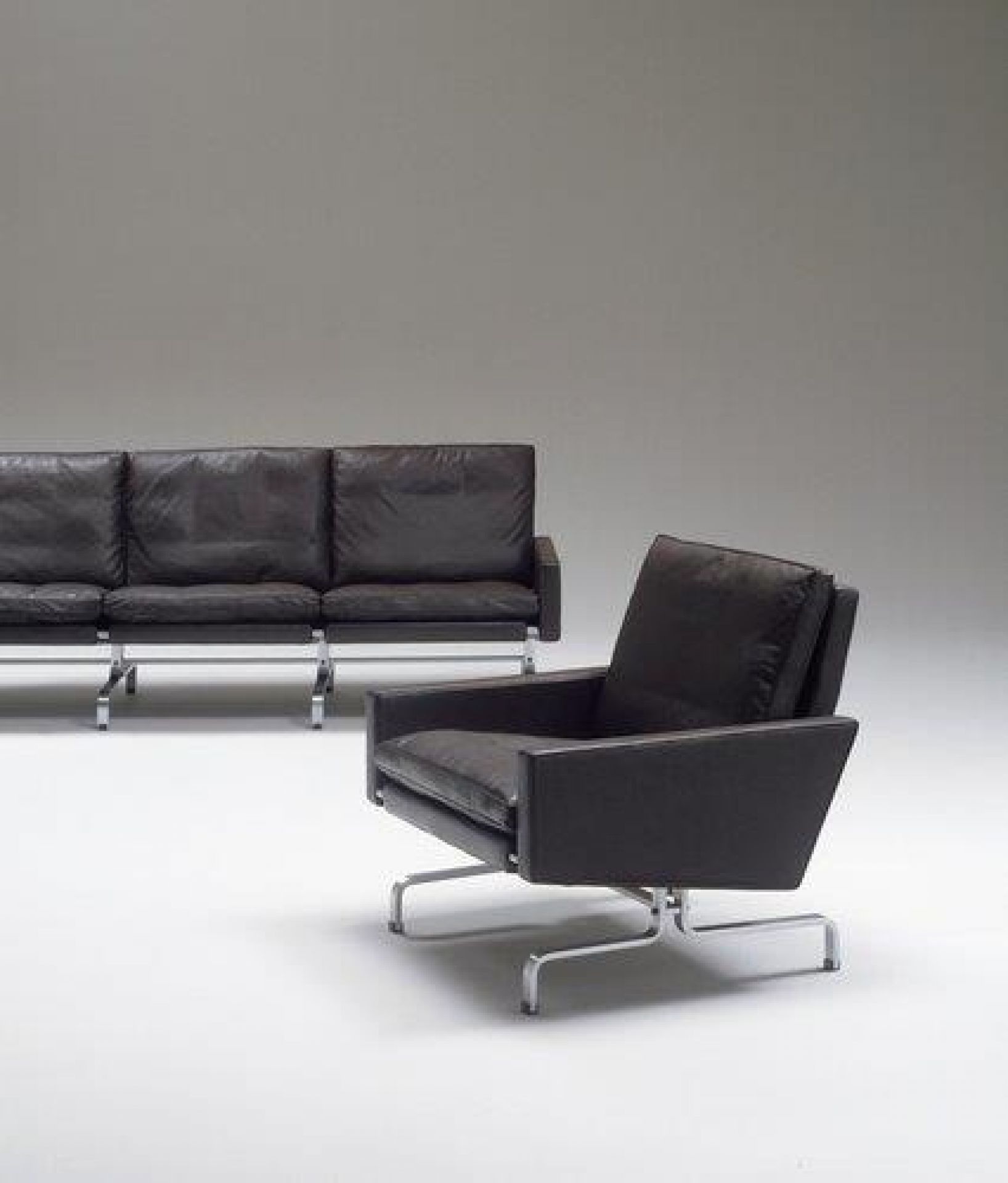 Schwarzer PK 31 Loungesessel von Fritz Hansen mit Ledersitz und Stahlgestell, passendes Sofa im Hintergrund.