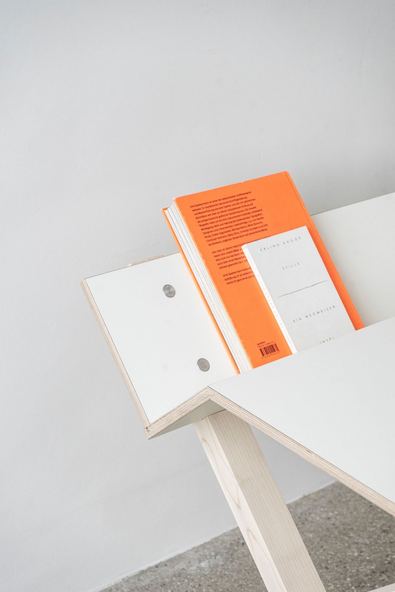 Detailaufnahme des Moormann Kant Schreibtischs: Weißes Tischblatt mit Holzgestell, darauf Bücher und minimalistisches Design.