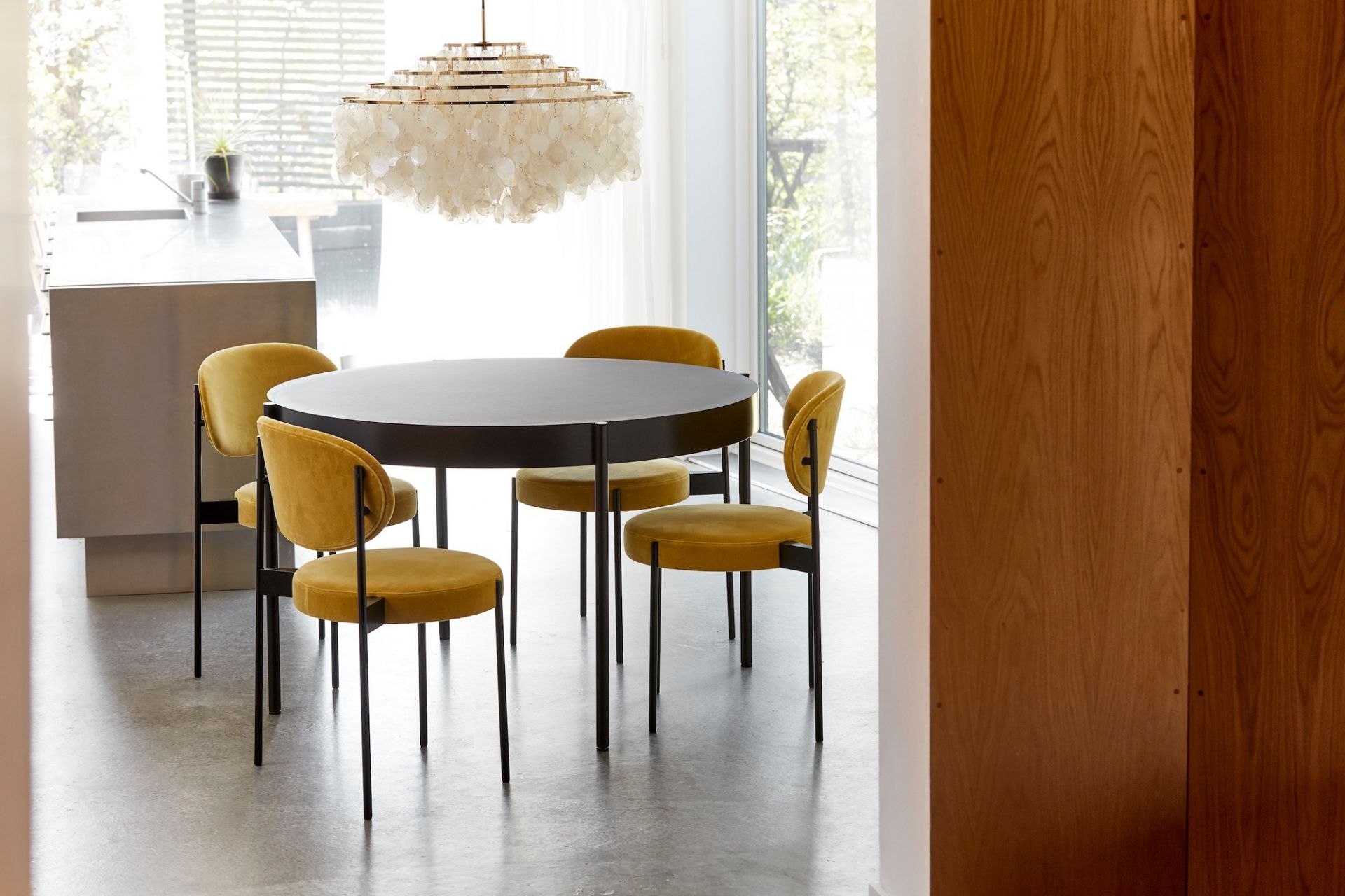 Verpan Series 430 Tisch mit gelben Stühlen und moderner Pendelleuchte in einem hellen Esszimmer.