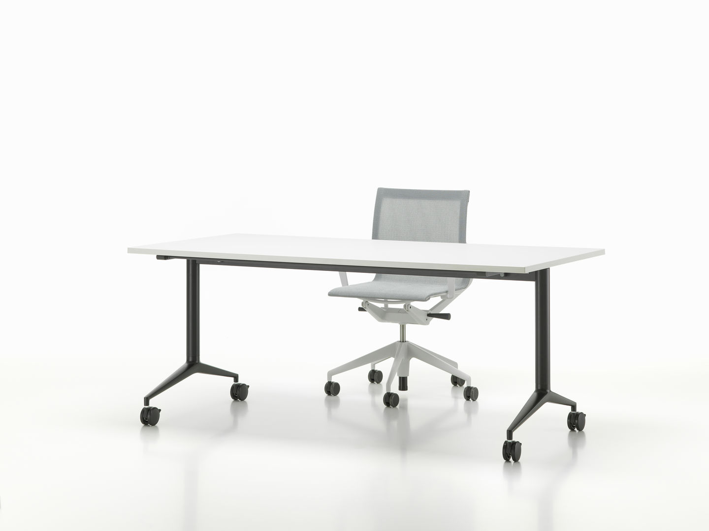 Vitra MedaMorph Klapptisch mit weißer Tischplatte und schwarzem Gestell, Bürostuhl im Hintergrund.