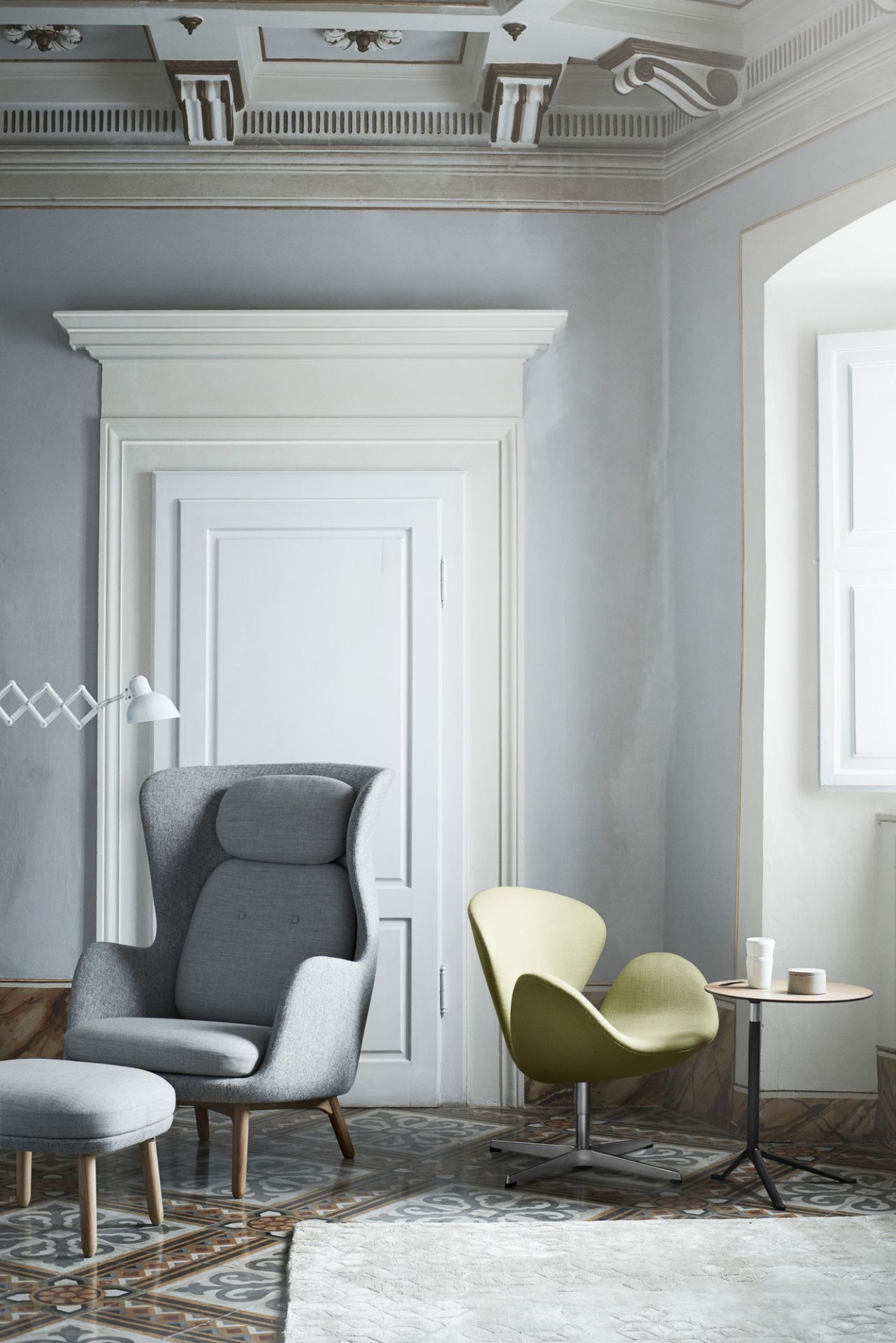Wohnzimmer Interieur mit Fritz Hansen Sesseln, Beistelltisch, KAISER idell Scherenleuchte und dekorativem Stuck an der Decke.