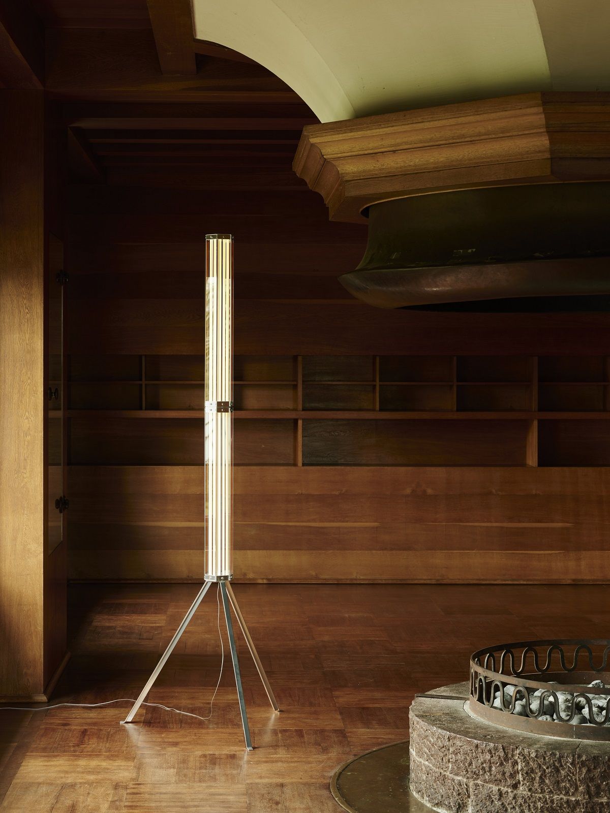 Superwire F Stehleuchte von Flos, moderne Stehlampe mit Tripod-Fuß in einem holzvertäfelten Raum.