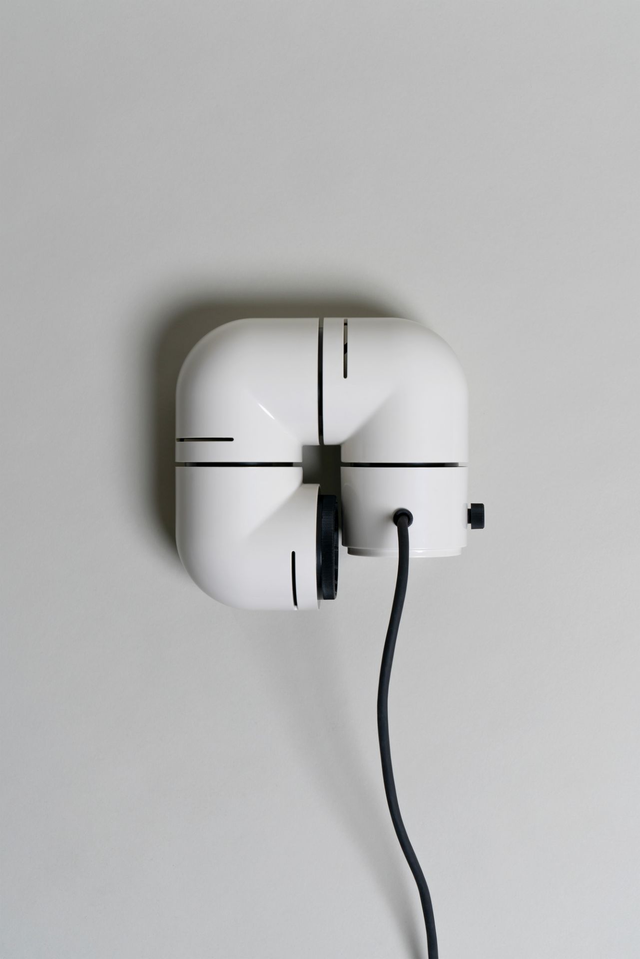 Weiße Tatu Tischleuchte von Santa & Cole, modernes Design mit schwarzem Kabel an einer Wand.