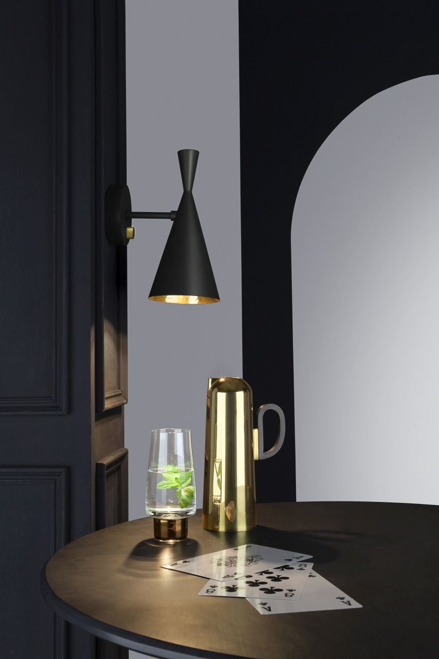 Schwarze Tom Dixon Beat Wandlampe über Tisch mit Glas Wasser, Krug und Spielkarten.
