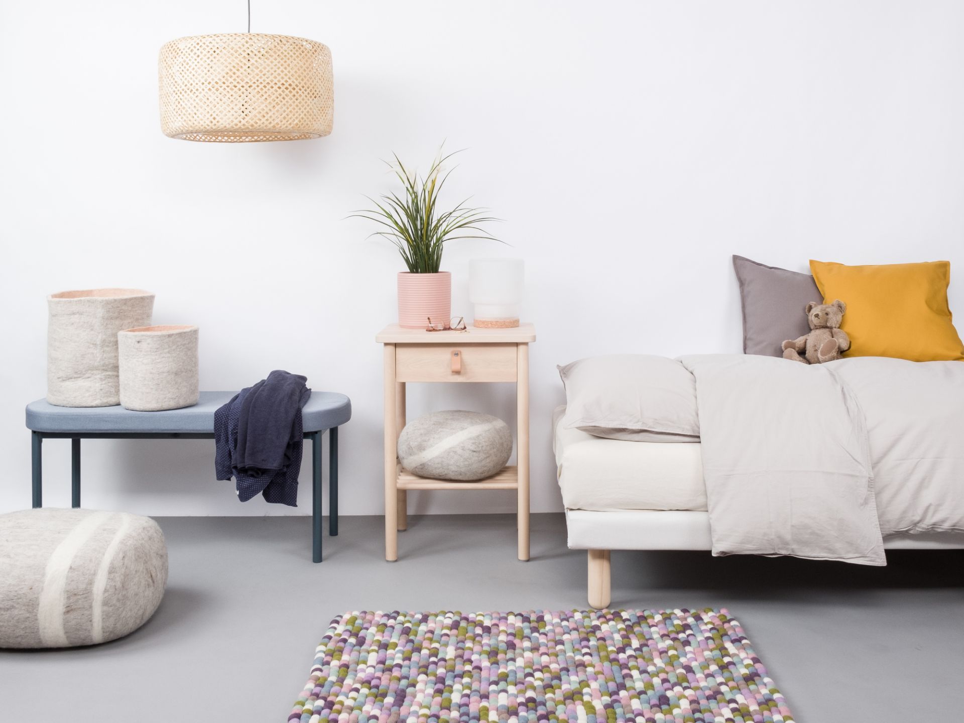 Farbenfroher Filzkugel Teppich von myfelt (120x170 cm) im modernen Schlafzimmer-Interieur. Handgefertigter Wollteppich.