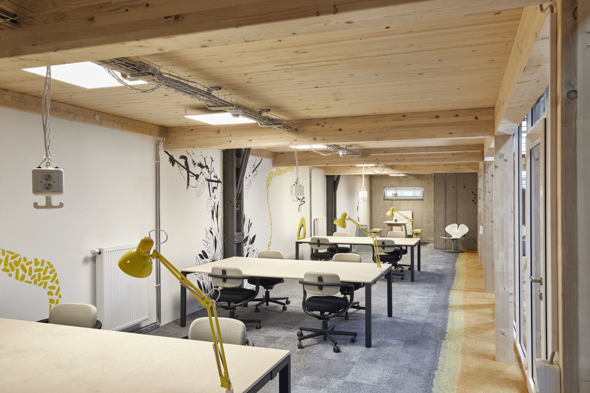 Helles Büro mit mehreren Allstar Bürodrehstühlen von Vitra und gelben Schreibtischlampen an Holztischen.