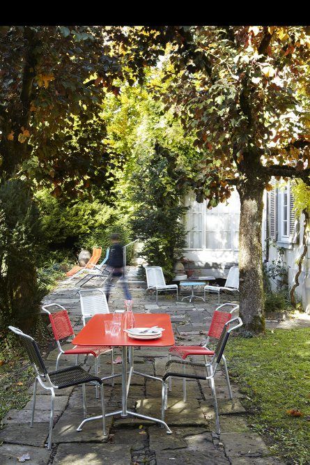 Altorfer Stuhl Outdoor Embru, altrosa, auf einer Terrasse mit Tisch und Stühlen im Garten.
