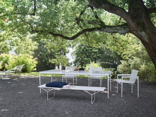 Bertoia Bank von Knoll International im Garten: Weiße Outdoor Bank mit blauem Kissen.