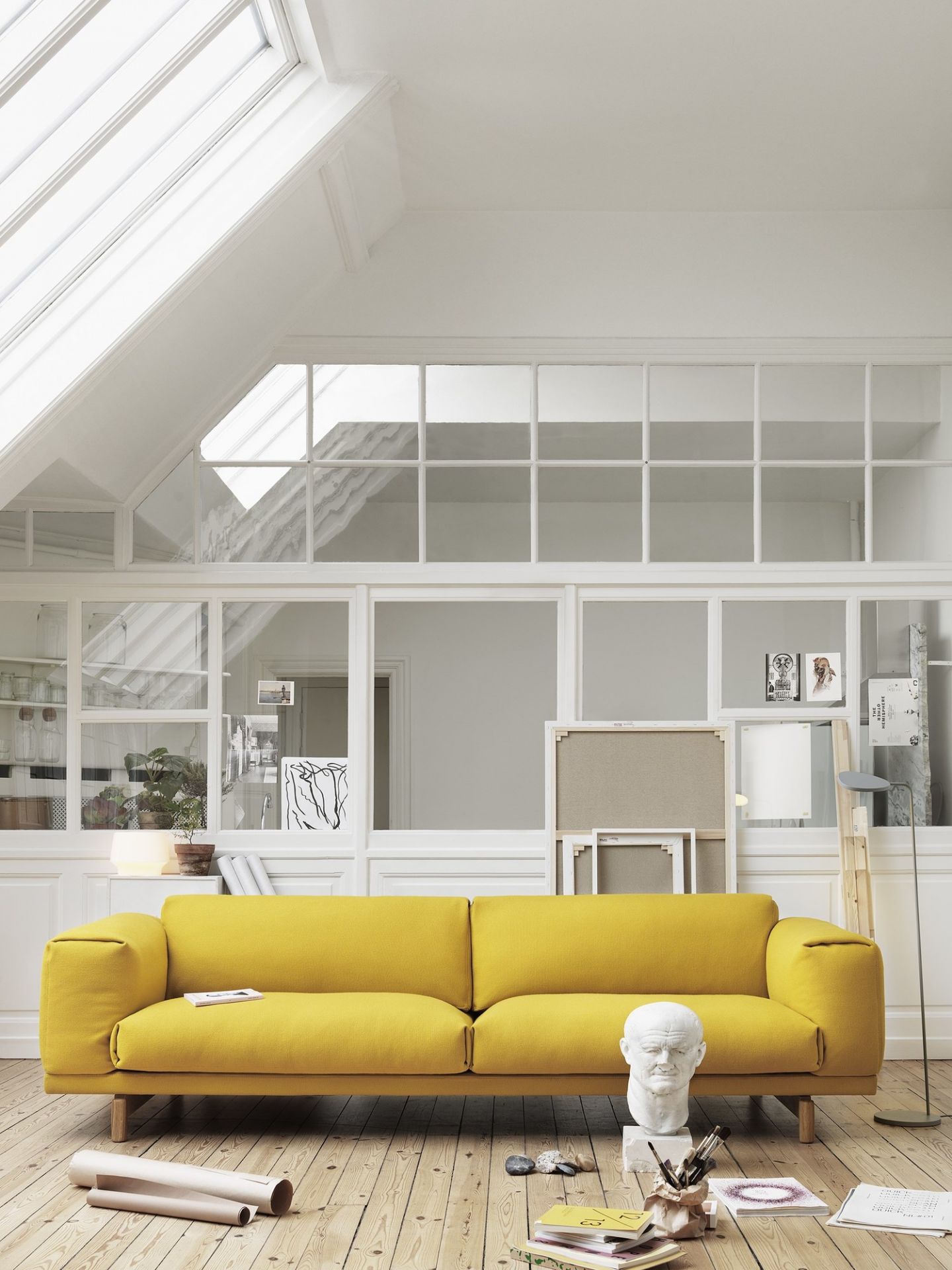 Helle Wohnzimmer-Szene mit gelbem Sofa und grauer Leaf Floor Lamp Stehleuchte von Muuto im Hintergrund.