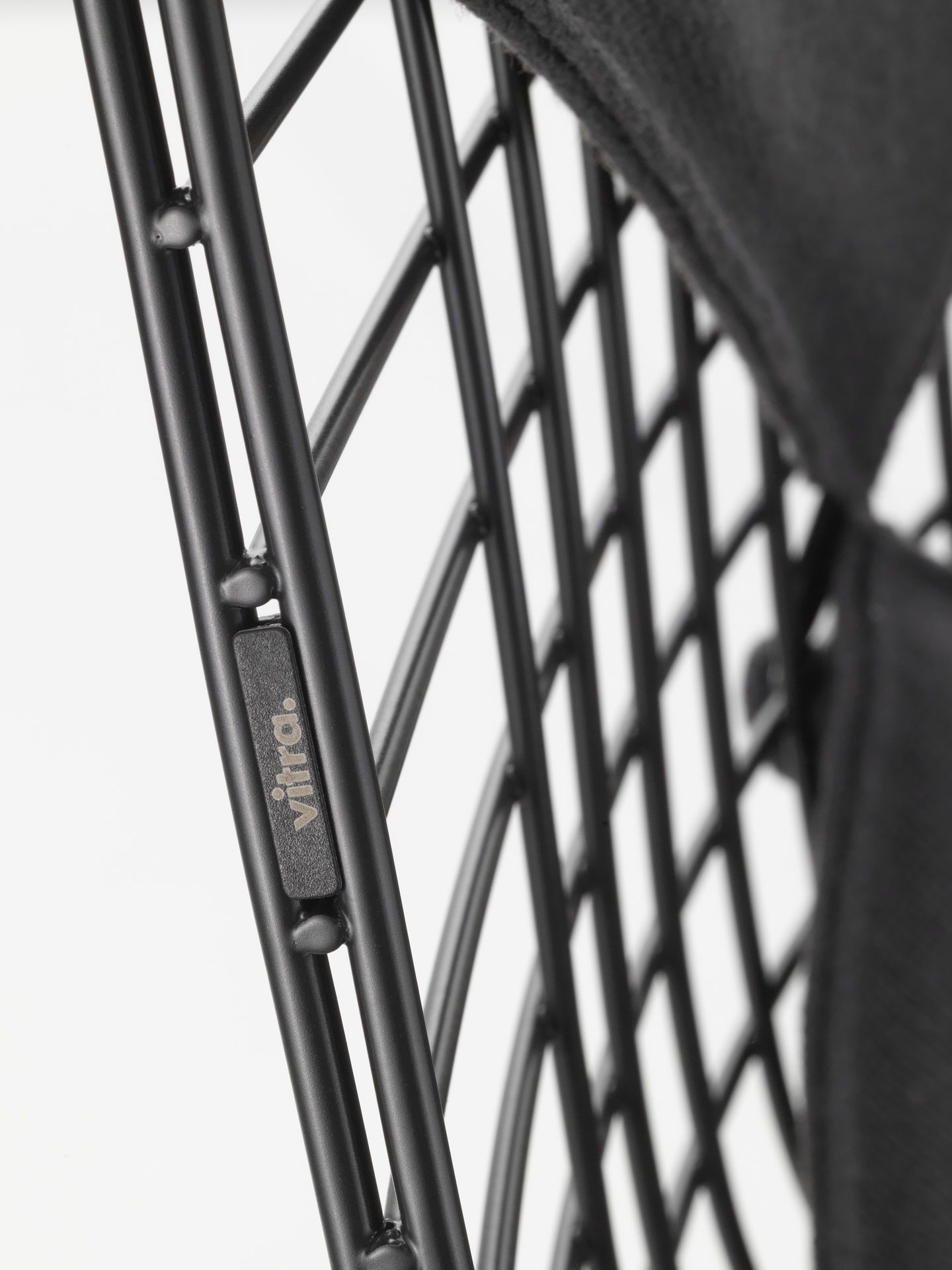 Detailaufnahme des Vitra DKR Wire Chair Stuhls mit schwarzem Sitzpolster und filigranem Drahtgestell.