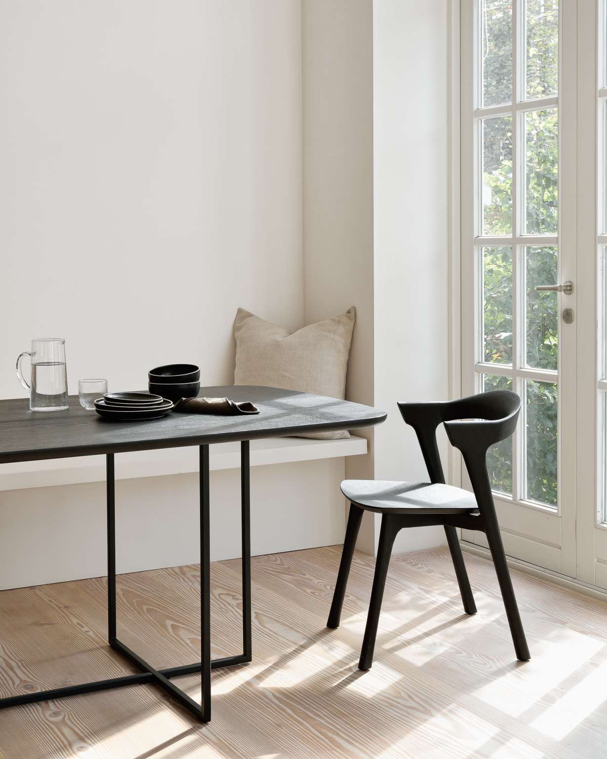 Beige Kissen auf einer Bank, passend zum minimalistischen Esszimmer mit Tisch und Stuhl.
