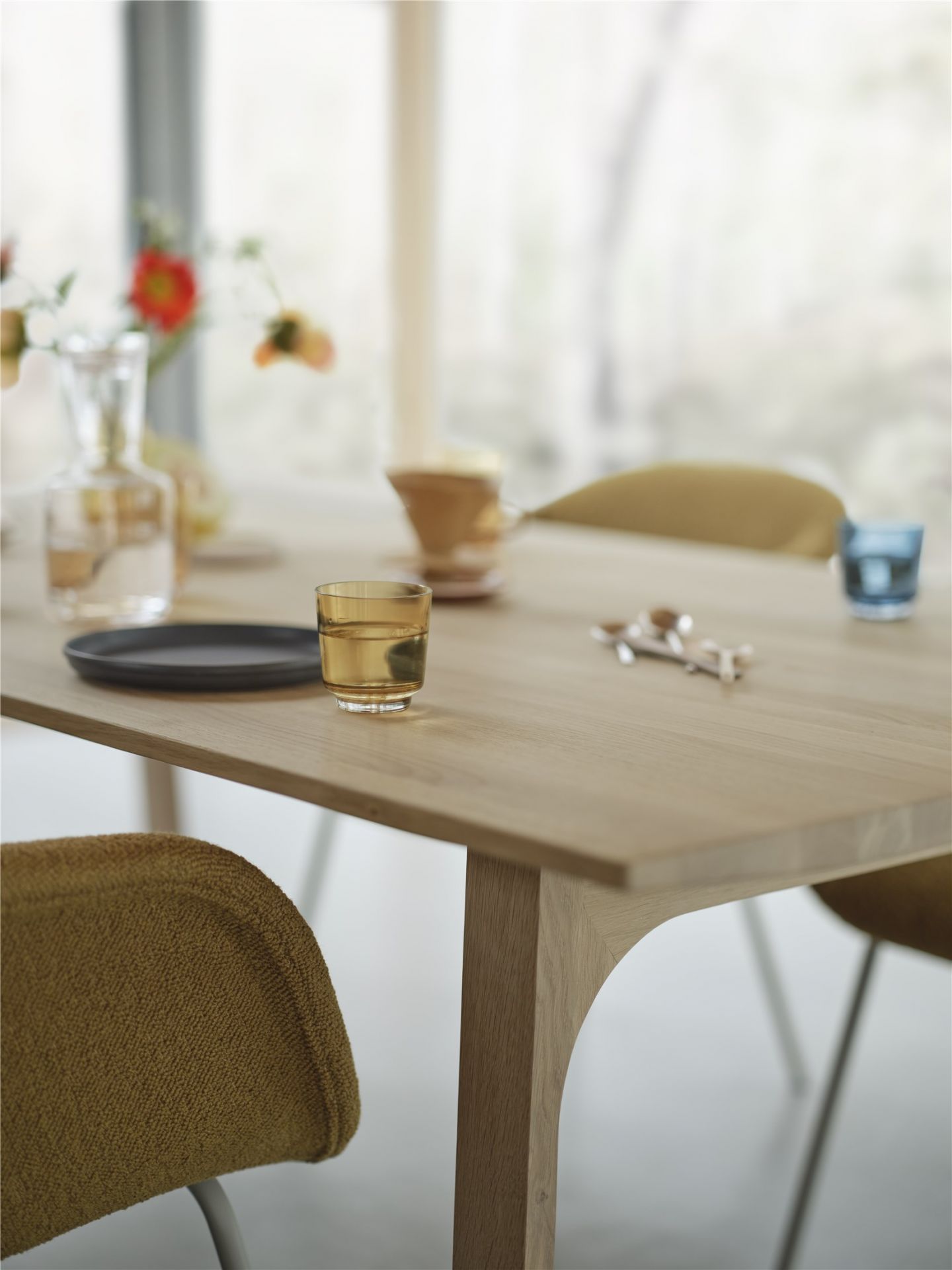 Nahaufnahme des Muuto Earnest Esstisches aus hellem Holz mit Stühlen und Tischdeko.