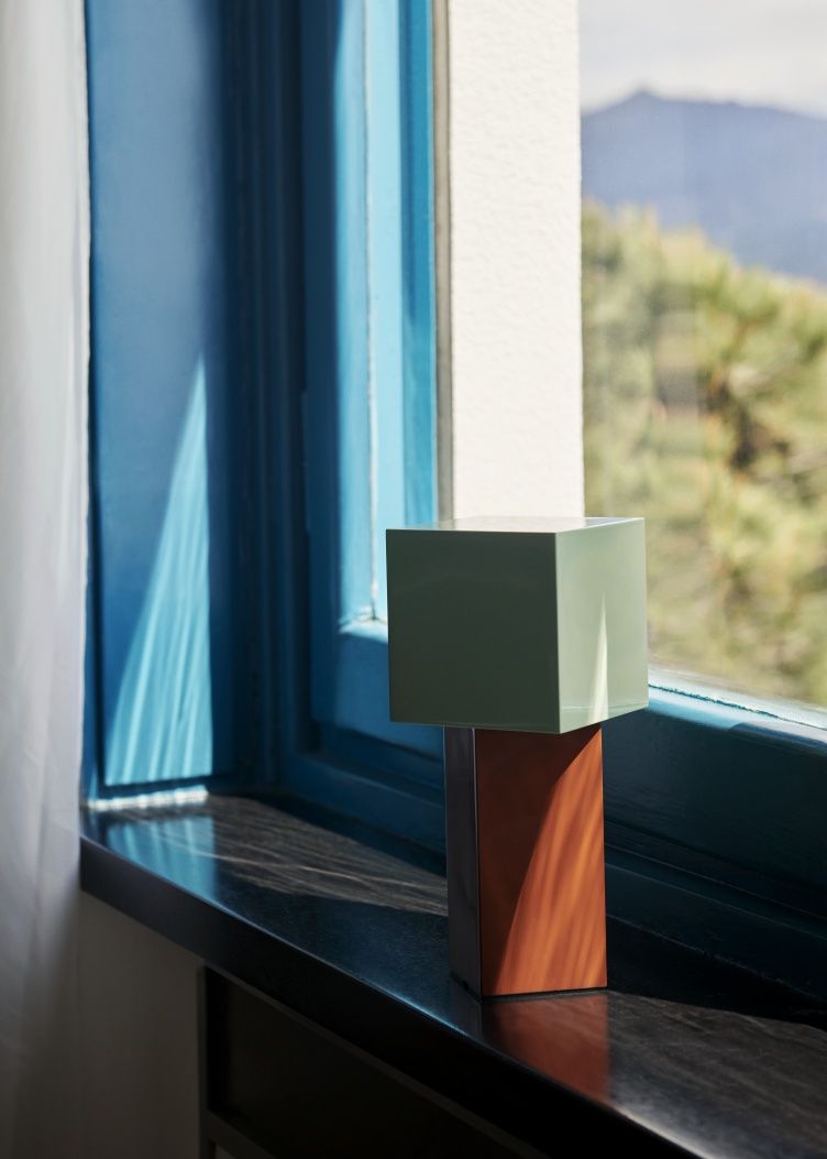 AndTradition Pivot ATD7 Akkuleuchte in Grün und Braun auf einer Fensterbank.