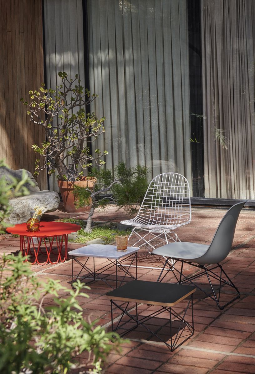 Eames Stuhl von Vitra, graue Sitzschale auf schwarzem Metallgestell, im Garten.