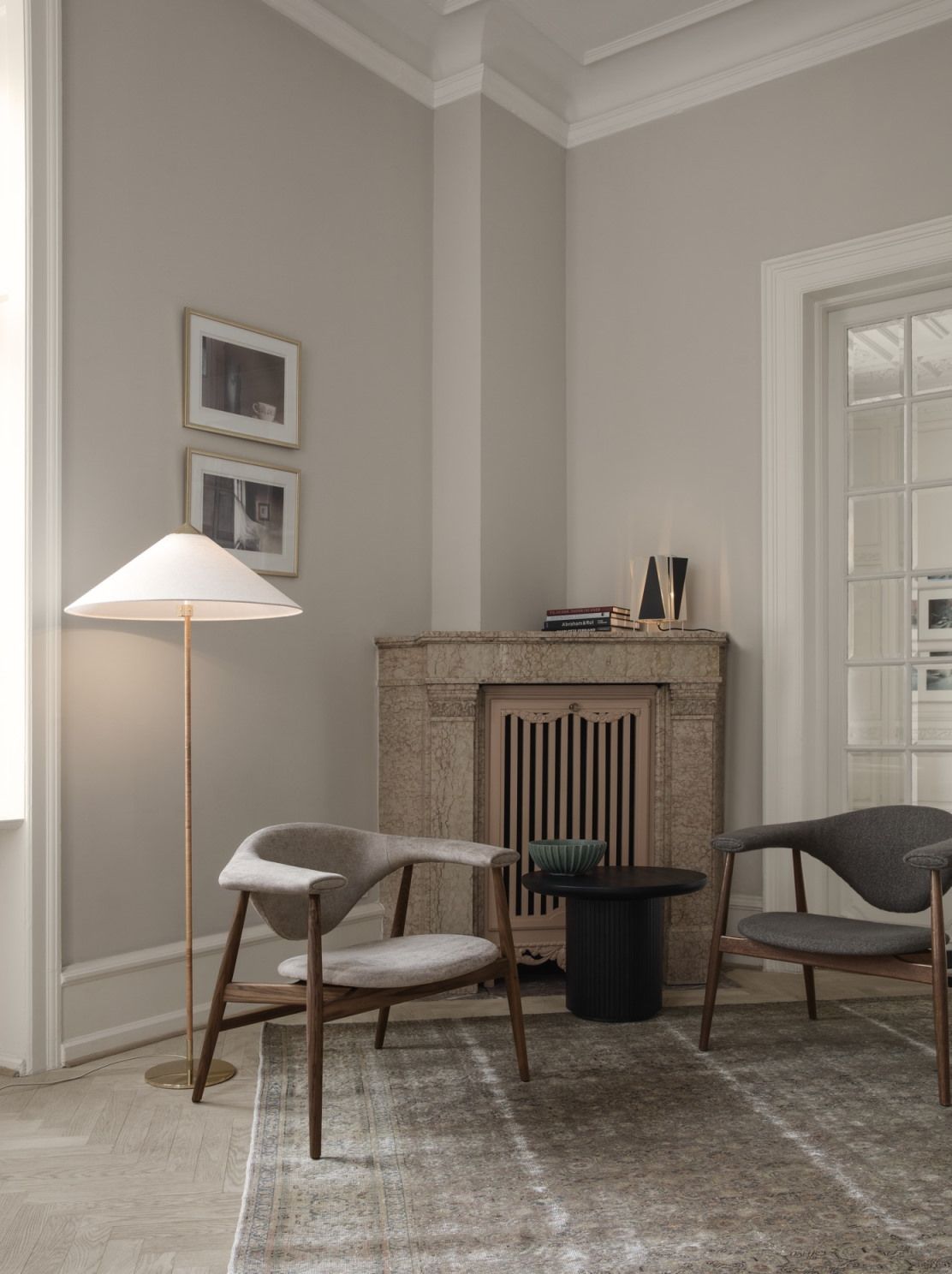Wohnzimmer mit Gubi Couchtisch Moon Coffee Table 60, Sesseln, Teppich und Kamin.