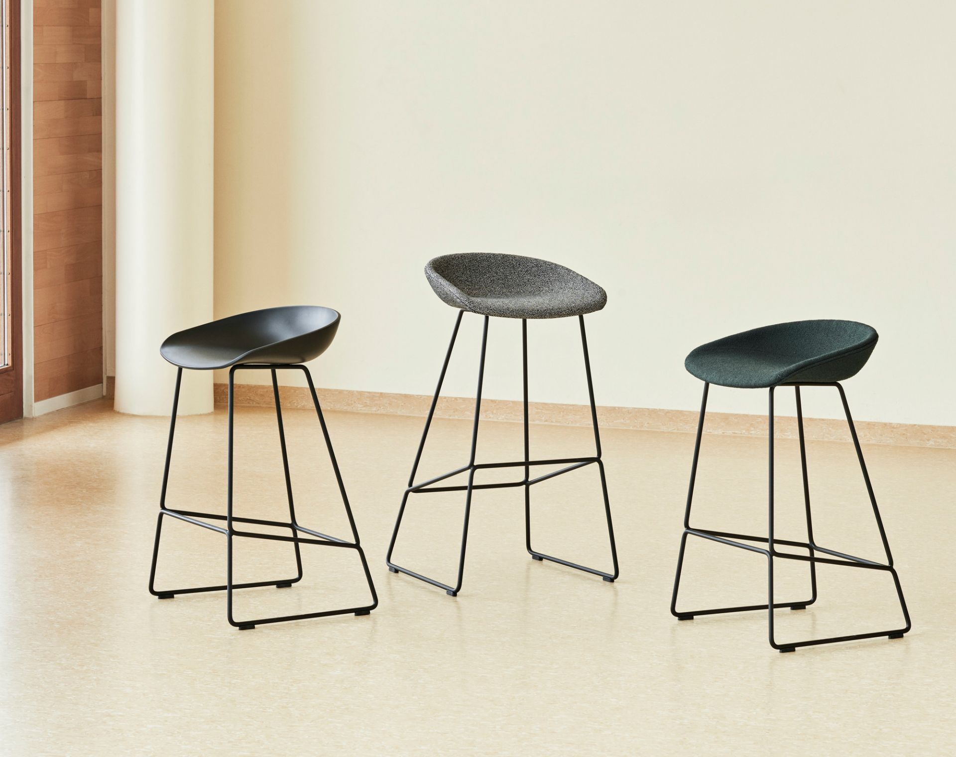 Drei About a Stool AAS 39 Barhocker mit Vollpolster in Schwarz, Grau und Grün.