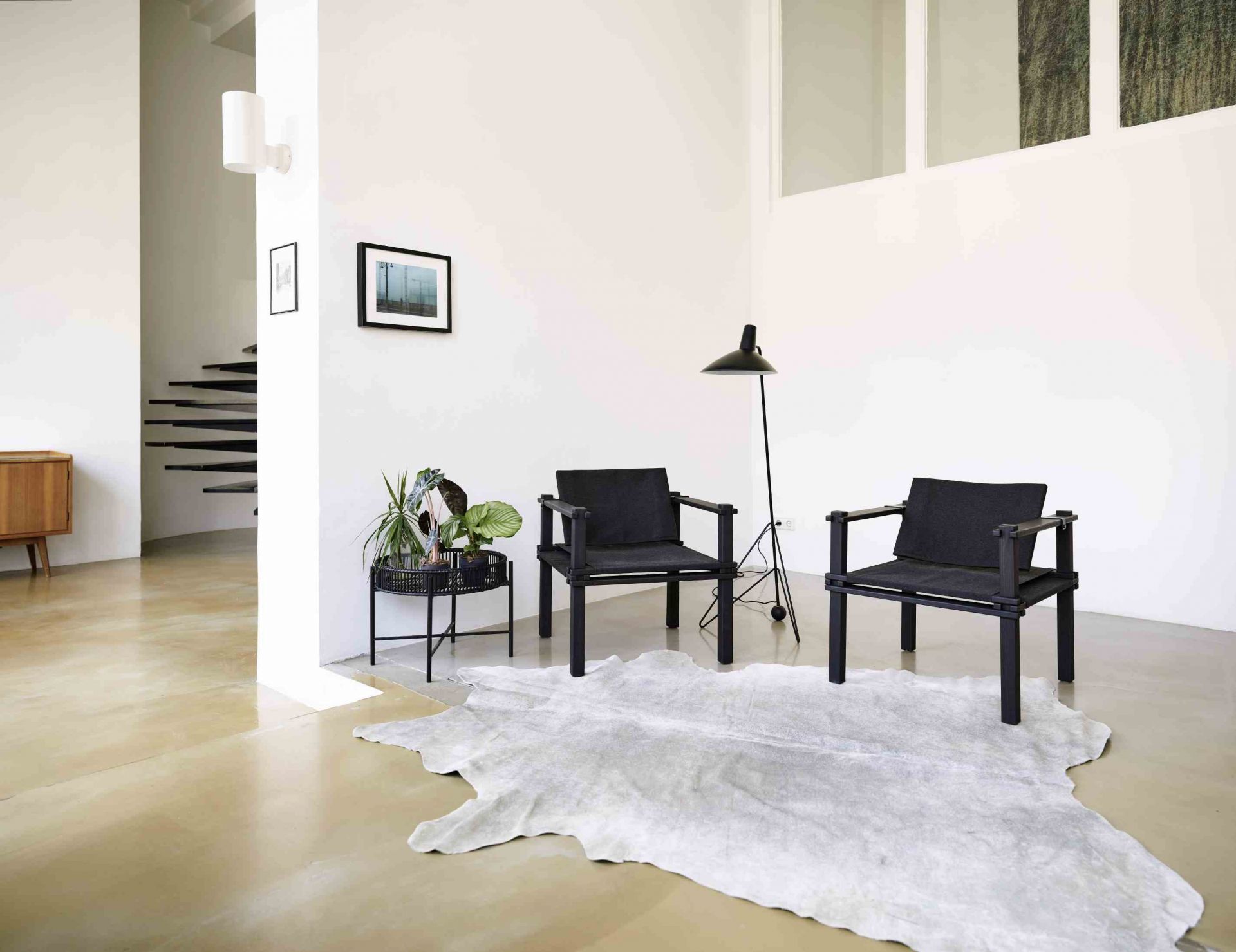 Zwei schwarze Farmer Sessel Outdoor Cor auf einem hellen Teppich in einem minimalistischen Wohnzimmer.