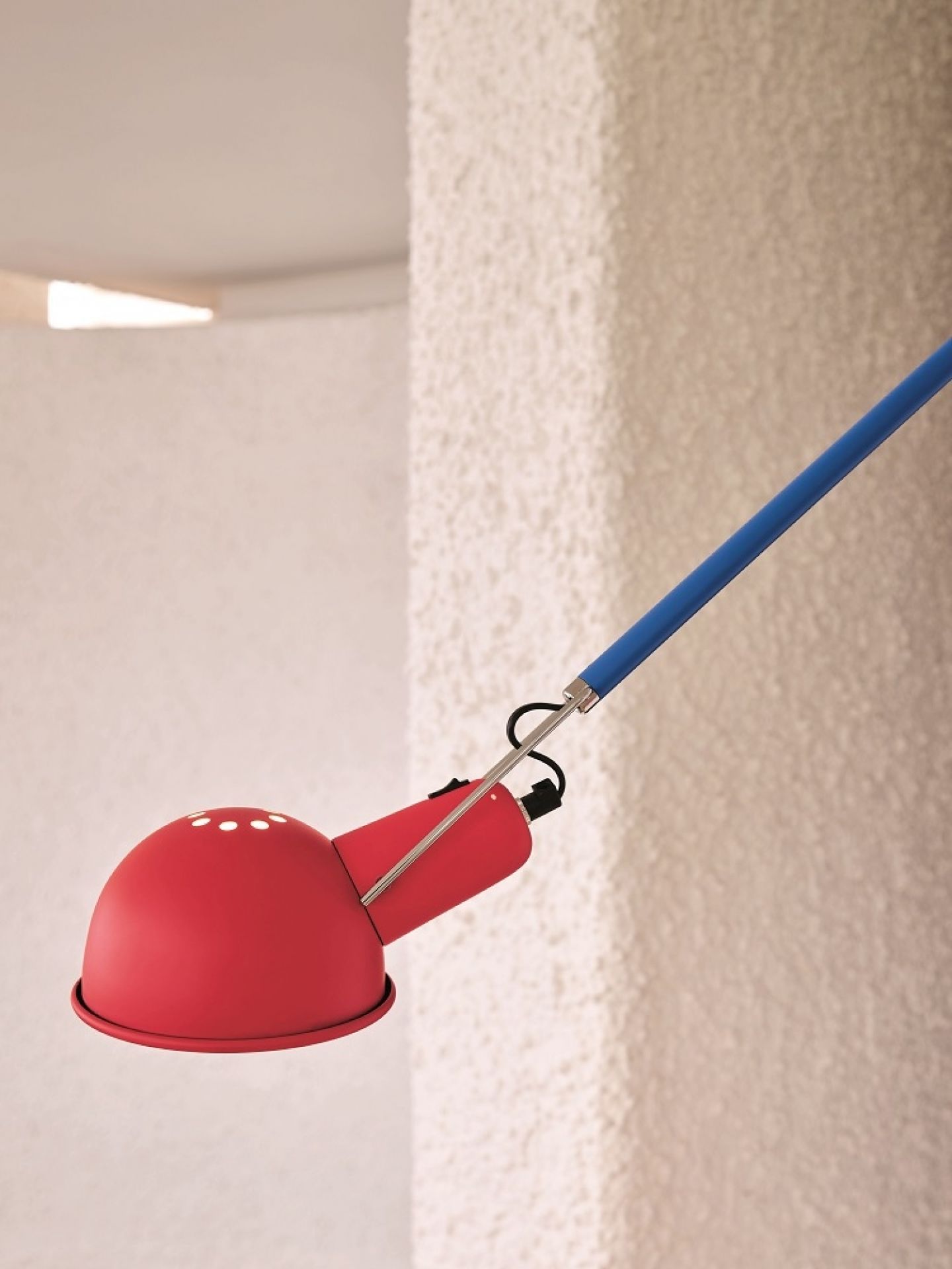 Nahaufnahme der roten Flos 265 Chromatica Wandleuchte mit blauem Arm vor weißer Wand.
