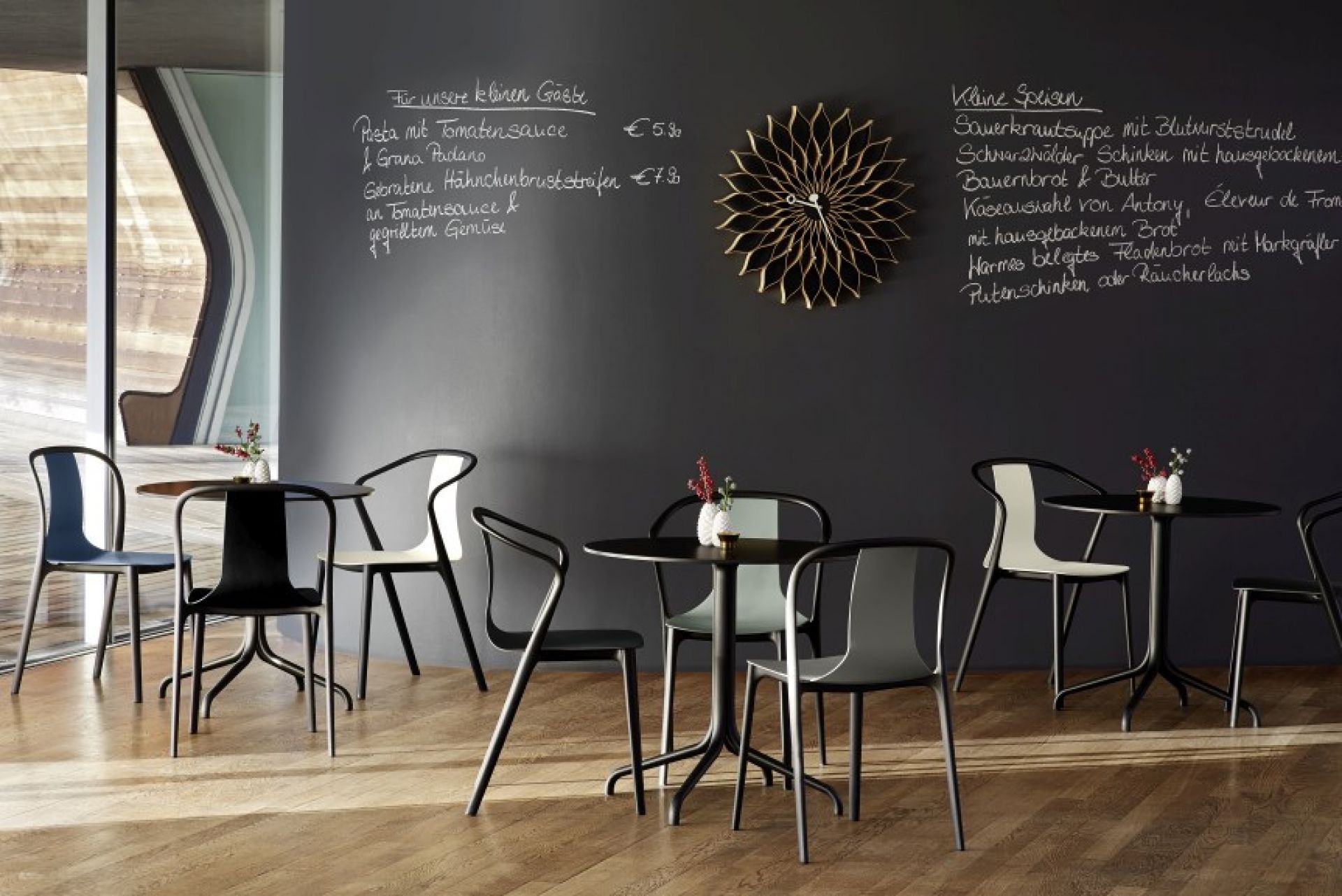 Vitra Belleville Table Tisch mit Stühlen in einem Restaurant mit Speisekarte an der Wand.