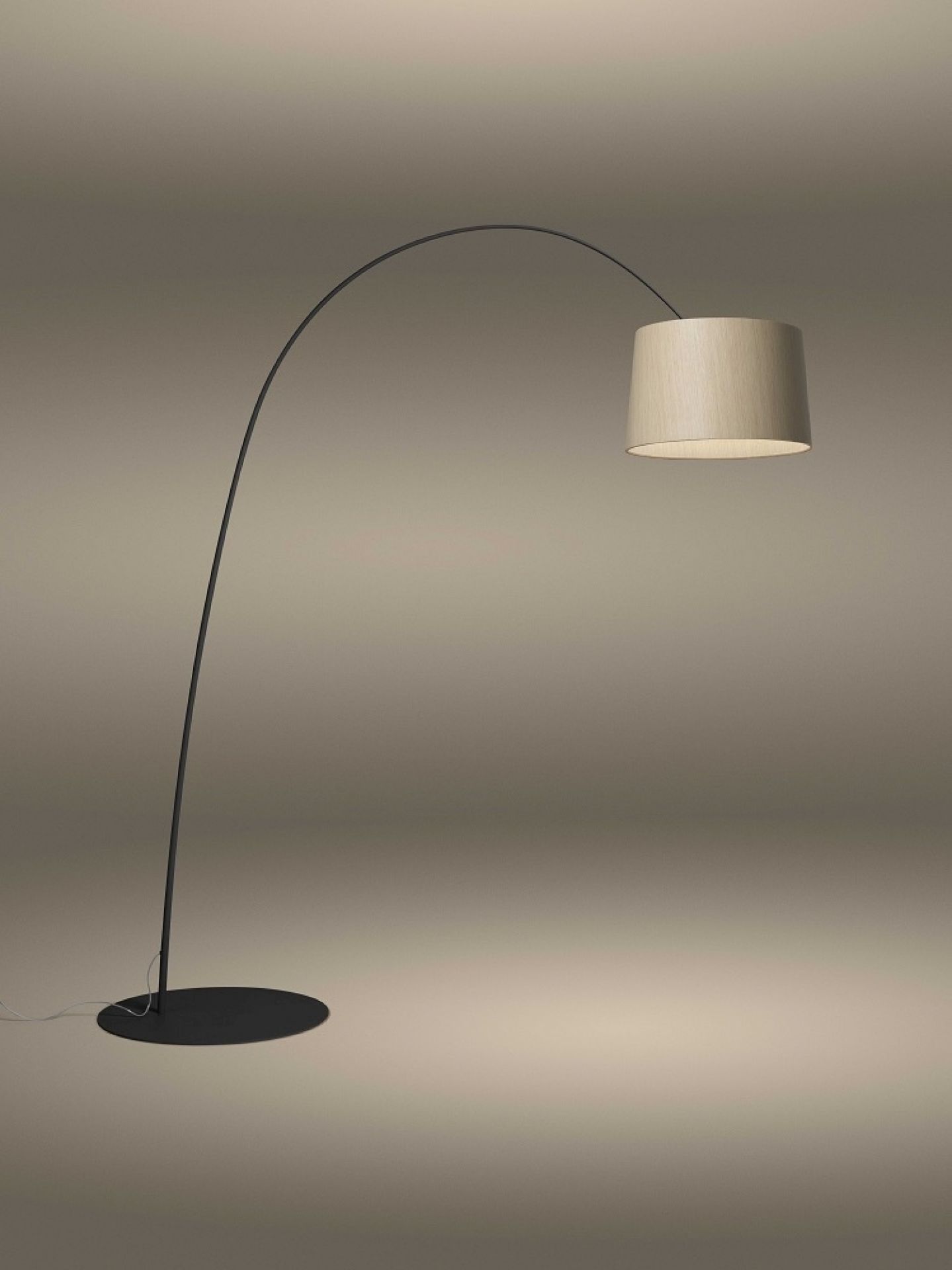 Twiggy Wood Stehleuchte von Foscarini mit gebogenem, schwarzem Lampenfuß und hellem Holzschirm.