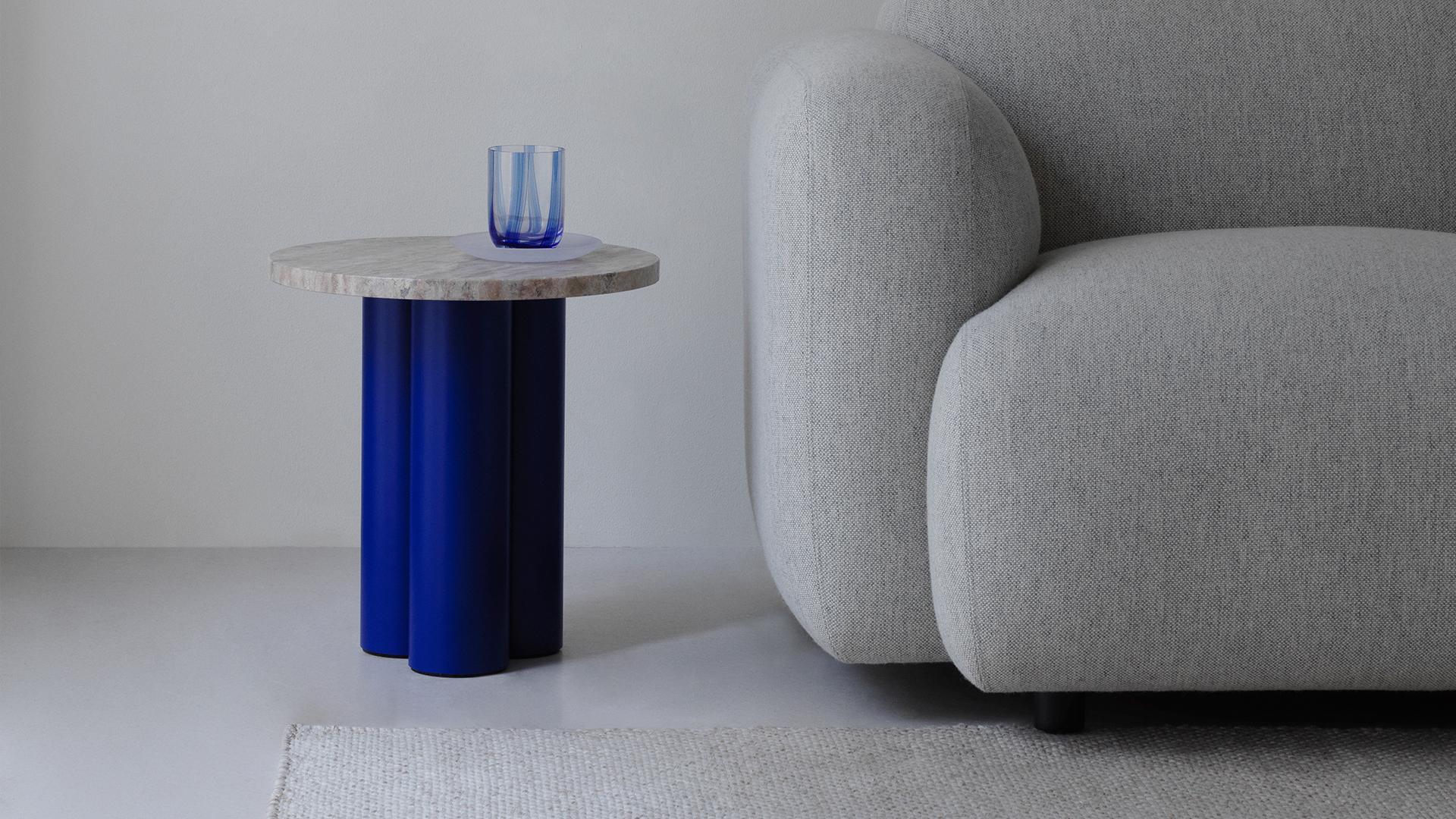 Dit Coffee Table Beistelltisch von Normann Copenhagen mit blauen Beinen und Marmorplatte neben Sofa.