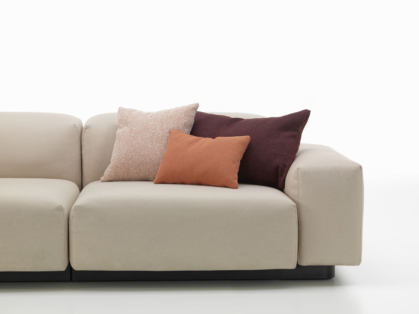 Beige Couch mit drei Zierkissen in Braun- und Rosatönen, Vitra Cushions Sofakissen für Wohnzimmer.