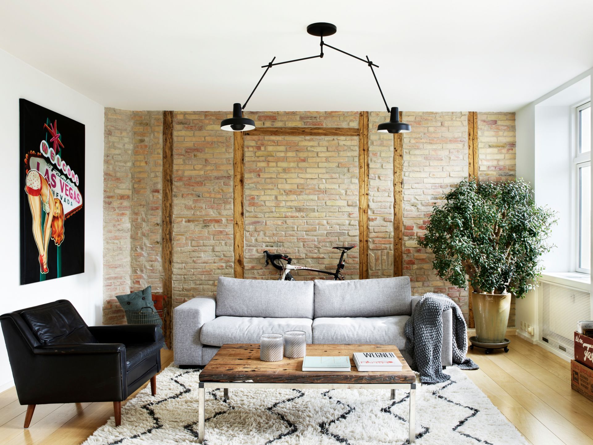 Wohnzimmer mit Arigato Deckenleuchte, schwarze Pendelleuchte über Sofa und Couchtisch.