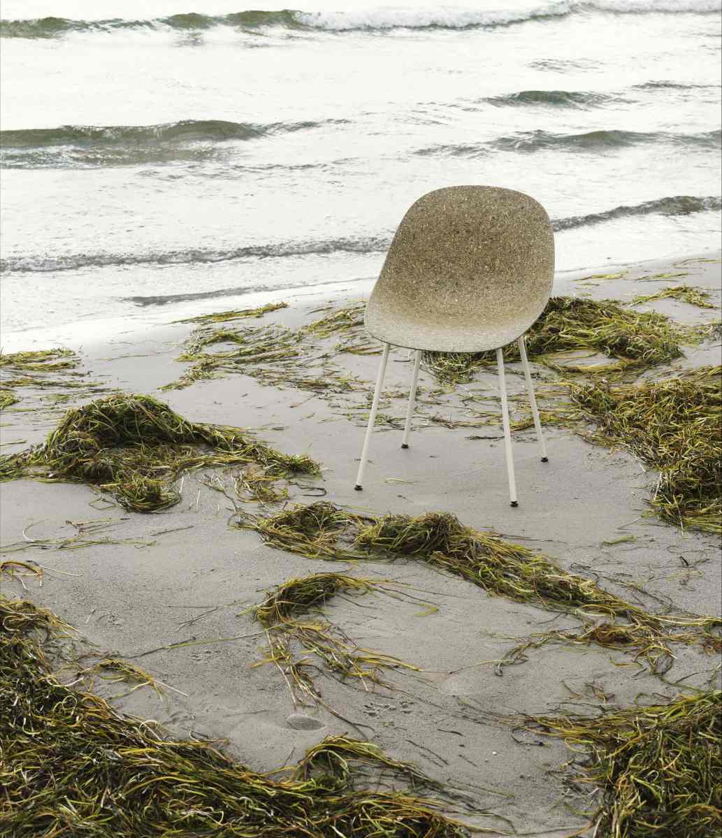 Normann Copenhagen Mat Chair Steel Stuhl auf einem Sandstrand mit Seetang und sanften Wellen.