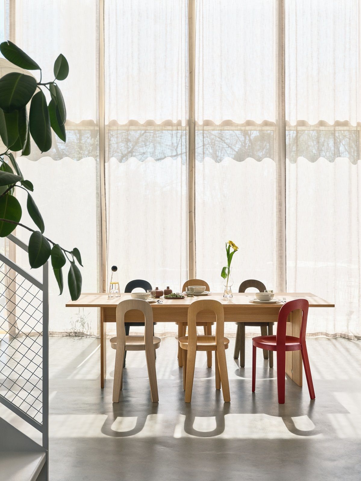 Esstisch mit Design House Stockholm Olivia Stühlen in verschiedenen Farben vor hellem Fenster.