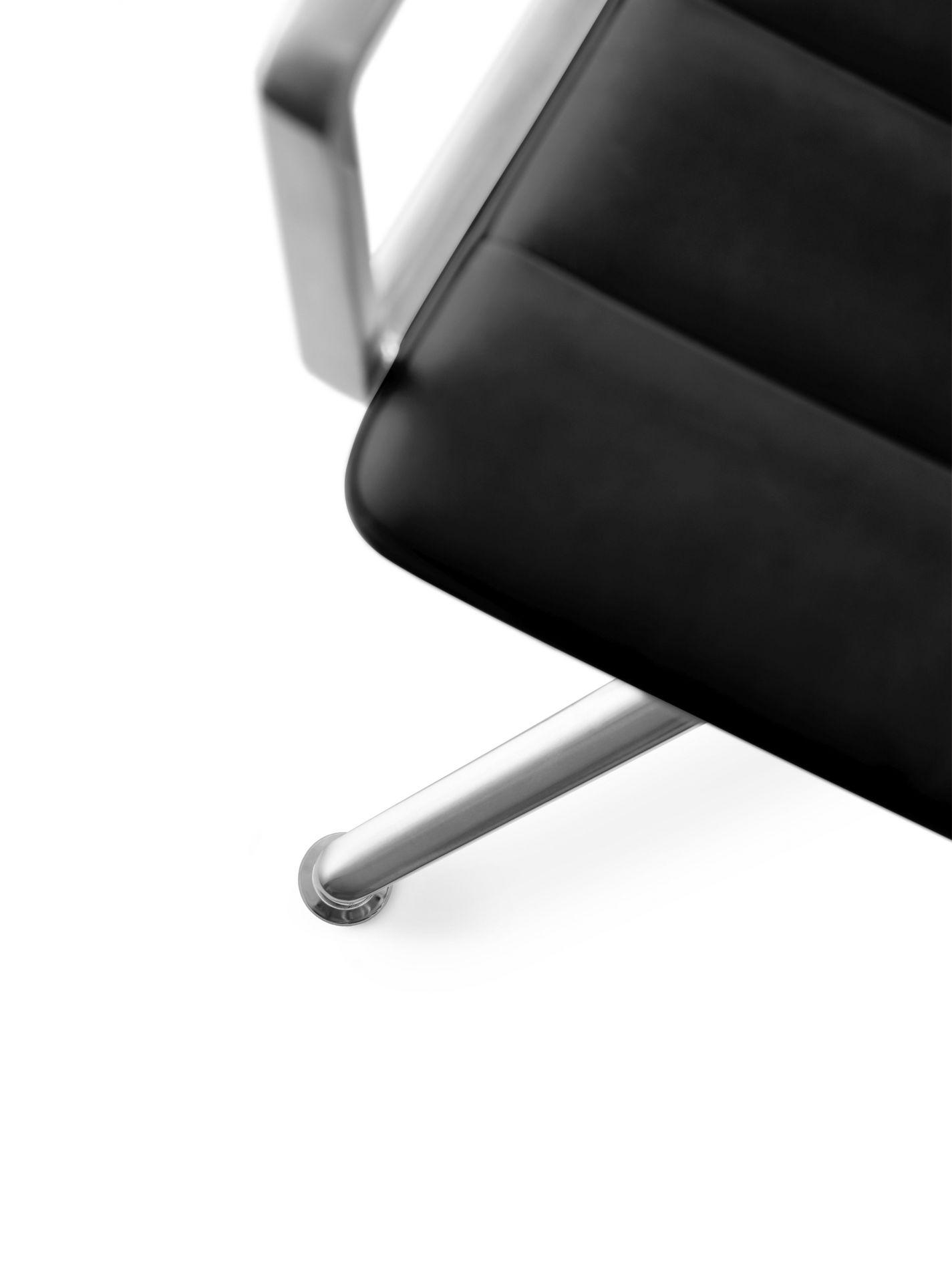 Detailaufnahme des Vipp Swivel Stuhls mit schwarzem Leder, Aluminium Armlehnen und Gleitern.