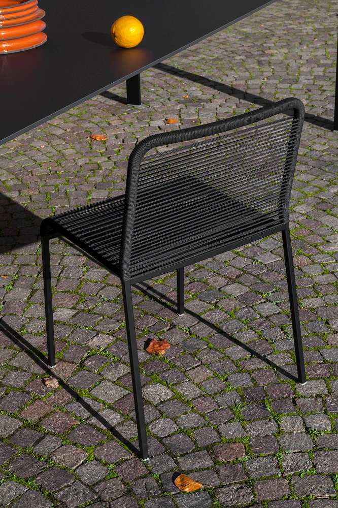 Schwarzer ARIA S42 Outdoor Stuhl von La Palma, stapelbarer Gartenstuhl mit Seilbespannung, Rückenansicht auf Pflastersteinen.