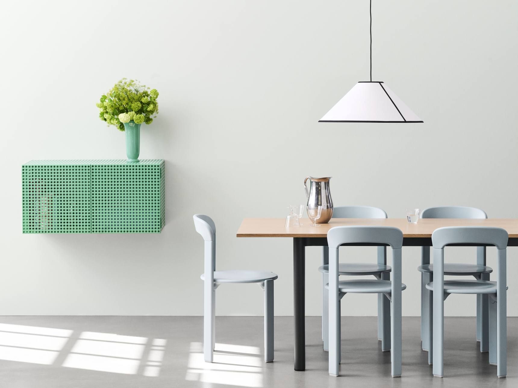 Helles Esszimmer mit Esstisch, Stühlen und grünem Hay Perforated Cabinet Wall Small Hängeschrank.