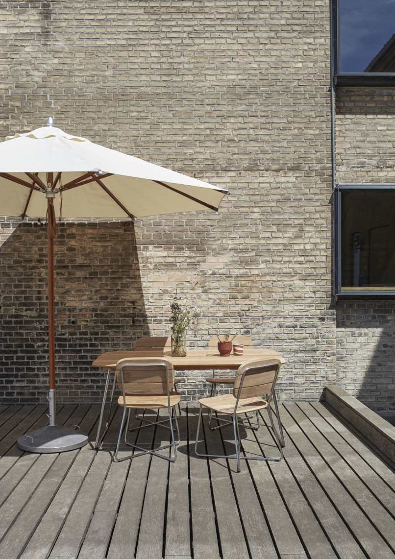 Capri Sonnenschirm mit Fuß von Skagerak by Fritz Hansen (50 kg) auf Holzterrasse.