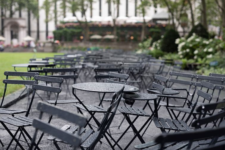 Reihe von schwarzen Fermob Bistro Tischen und Stühlen im Freien an einem regnerischen Tag.