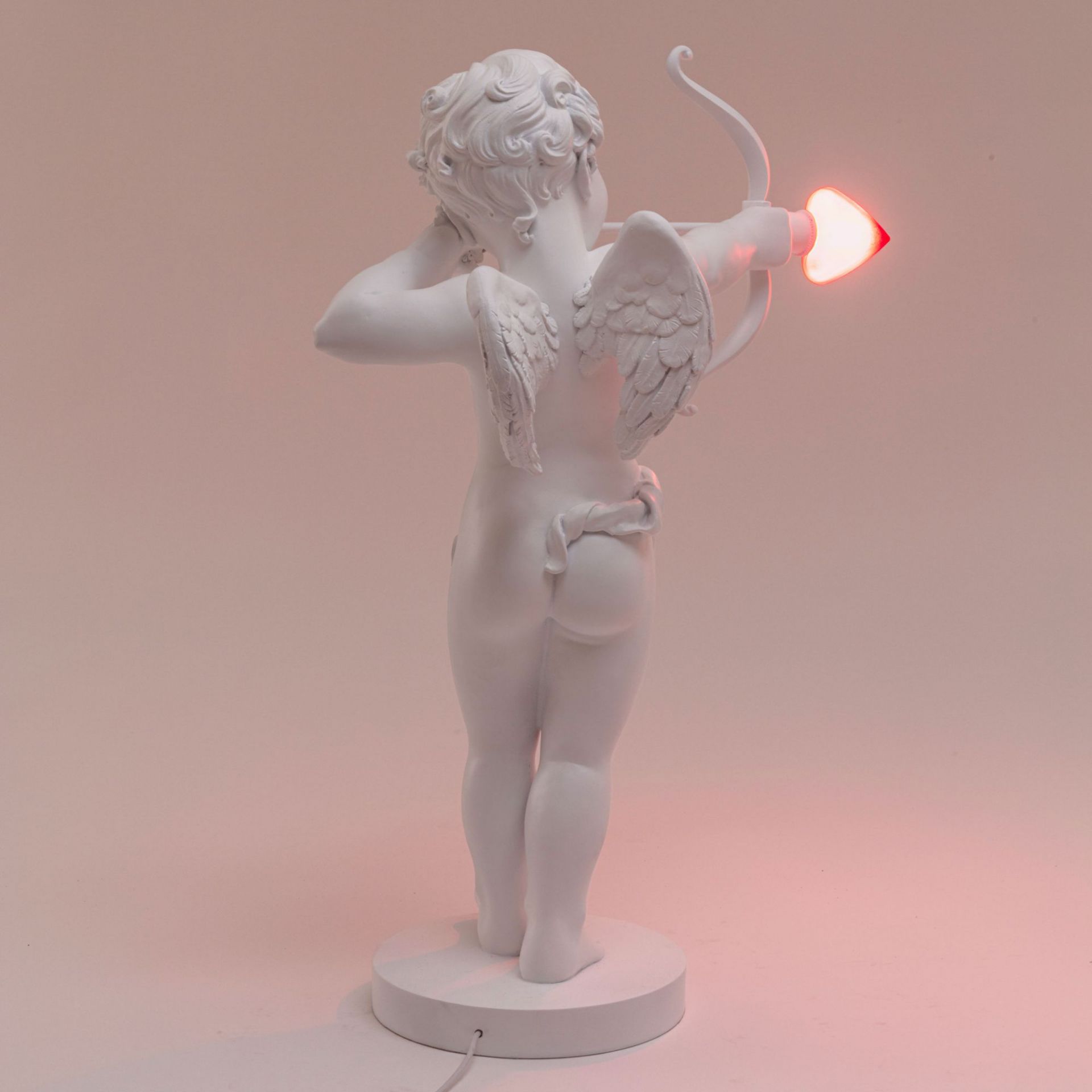 Rückansicht der Seletti Cupid Lampe, Amor Figur mit Pfeil als Leuchtmittel.