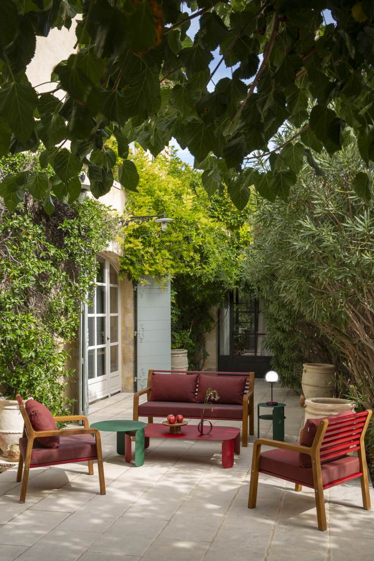 Fermob Somerset Sessel und Gartenmöbel-Set in Rot und Grün auf einer Terrasse im Freien.