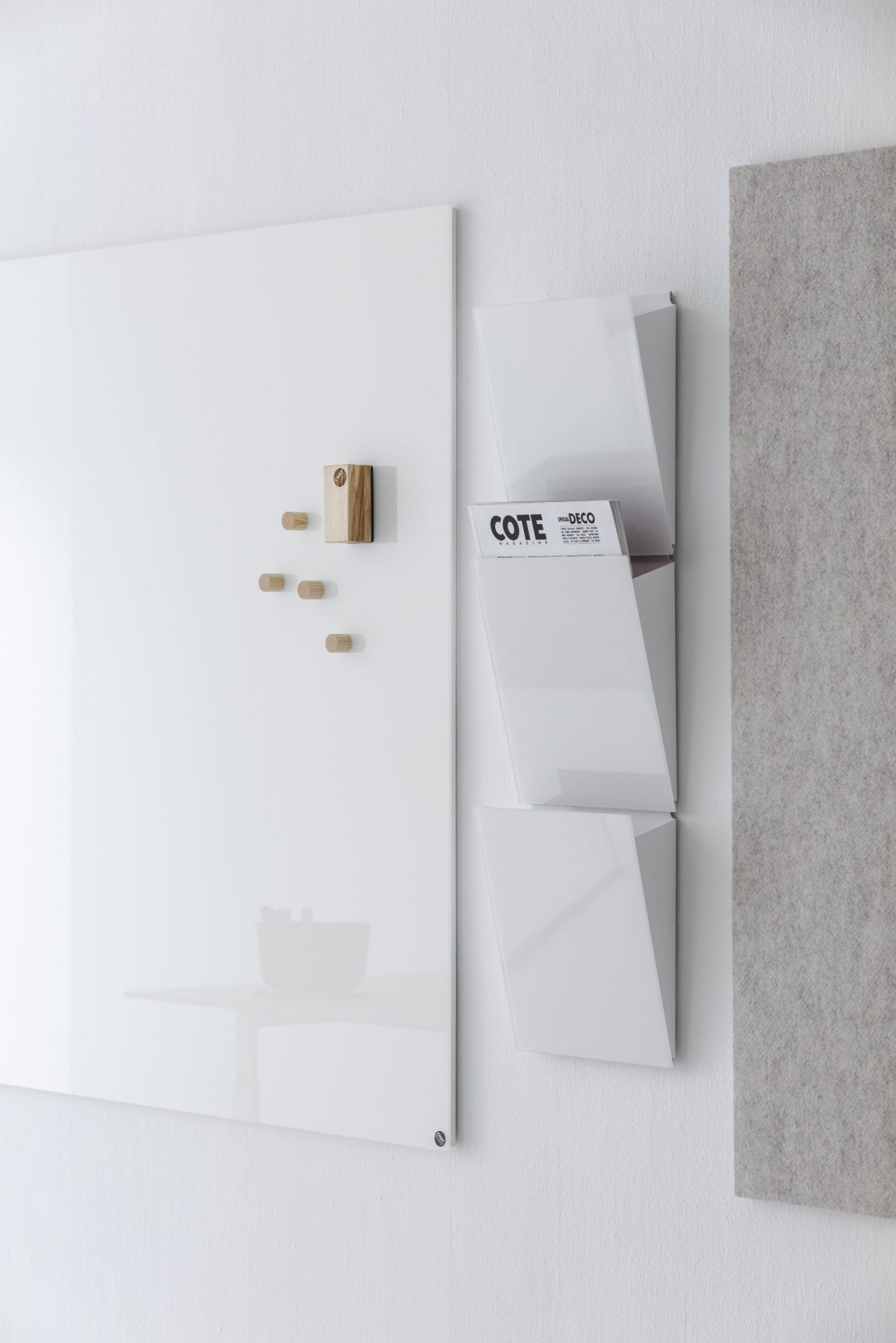 Weiße Chat Board Classic Glastafel an der Wand mit Holzmagneten und Magazinhalter.