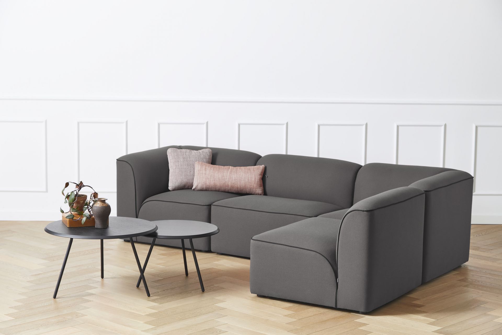 Graues Flora Modulsofa von Woud mit Kissen und Beistelltischen auf hellem Holzboden.