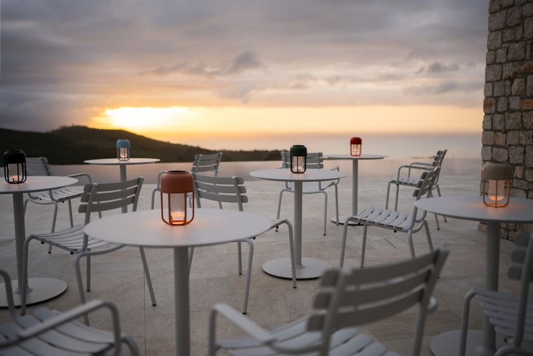 Alua Armrest Dining Chair von Houe im Außenbereich bei Sonnenuntergang. Gartenmöbel mit Armlehnen.