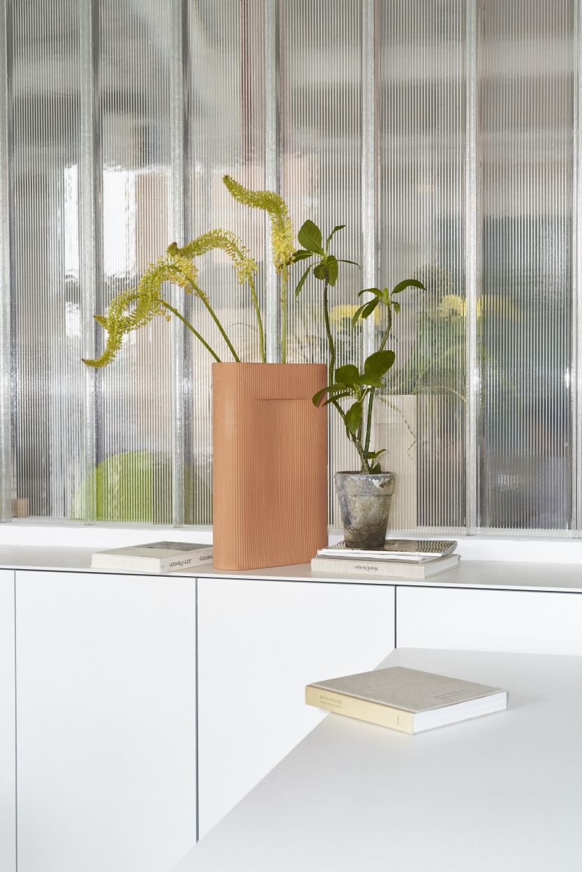 Nahaufnahme der Muuto Ridge Vase in Terrakotta mit Blumen auf einem weißen Sideboard.
