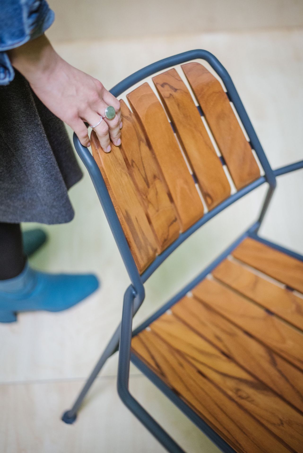 Detailaufnahme: Osmo Teak Stuhl von Prostoria mit Holzlatten und grauem Metallgestell. Outdoor-Möbel.