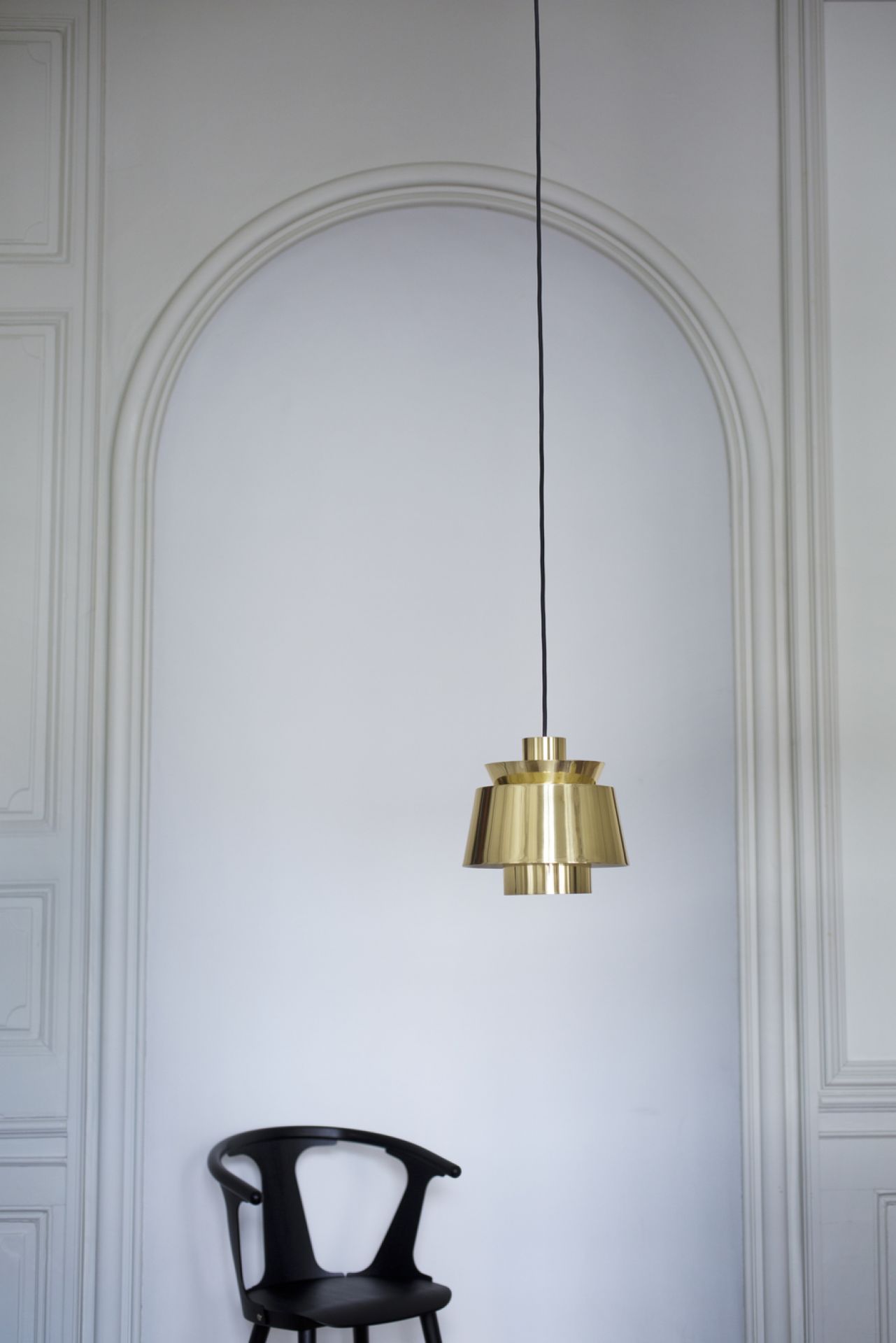 Nahaufnahme der AndTradition Utzon Pendelleuchte aus Messing, hängend vor einer weißen Wand.