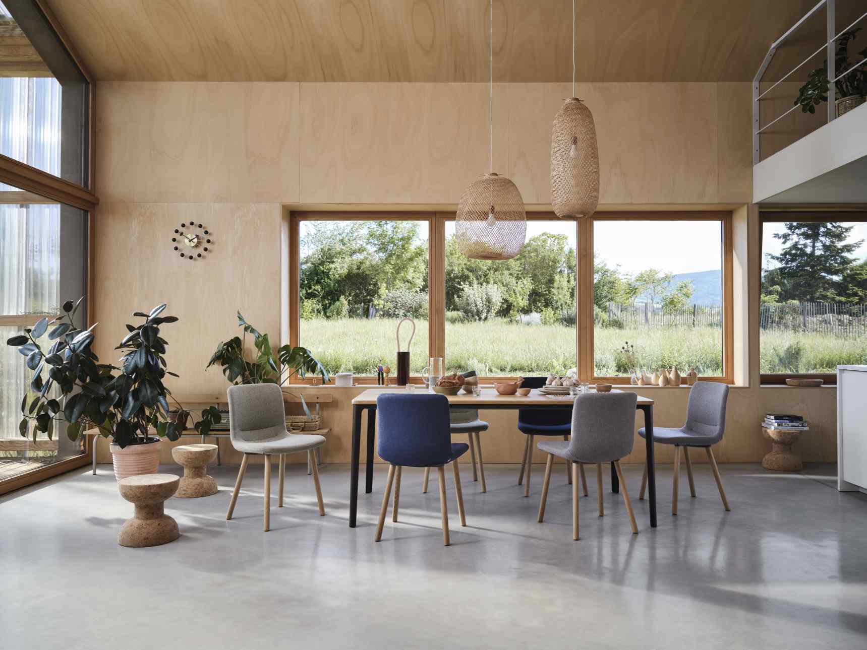 Esstisch mit Stühlen in Grau und Blau, moderne Pendelleuchten aus Rattan, helle Einrichtung.