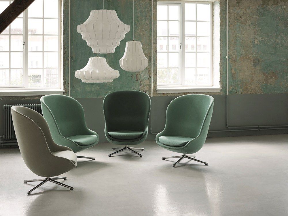 Normann Copenhagen Hyg Lounge Sessel mit Drehgestell in verschiedenen Farben und Pendelleuchten in einem Raum.
