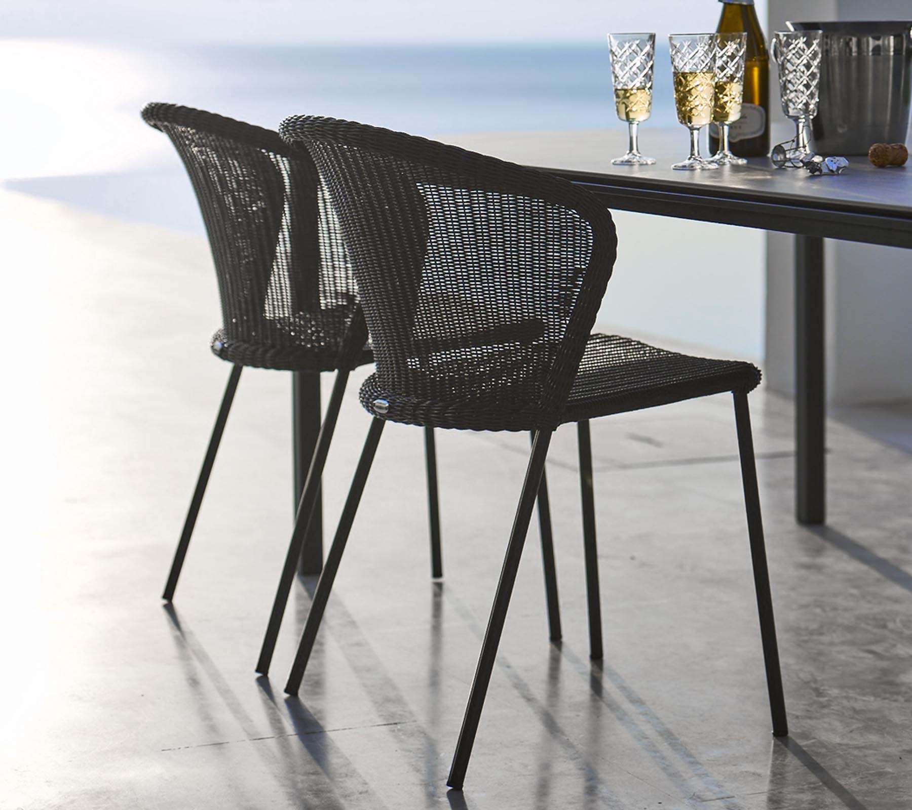 Zwei schwarze Lean Stühle mit grauem Kissen von Cane-Line aus Rattan Geflecht.