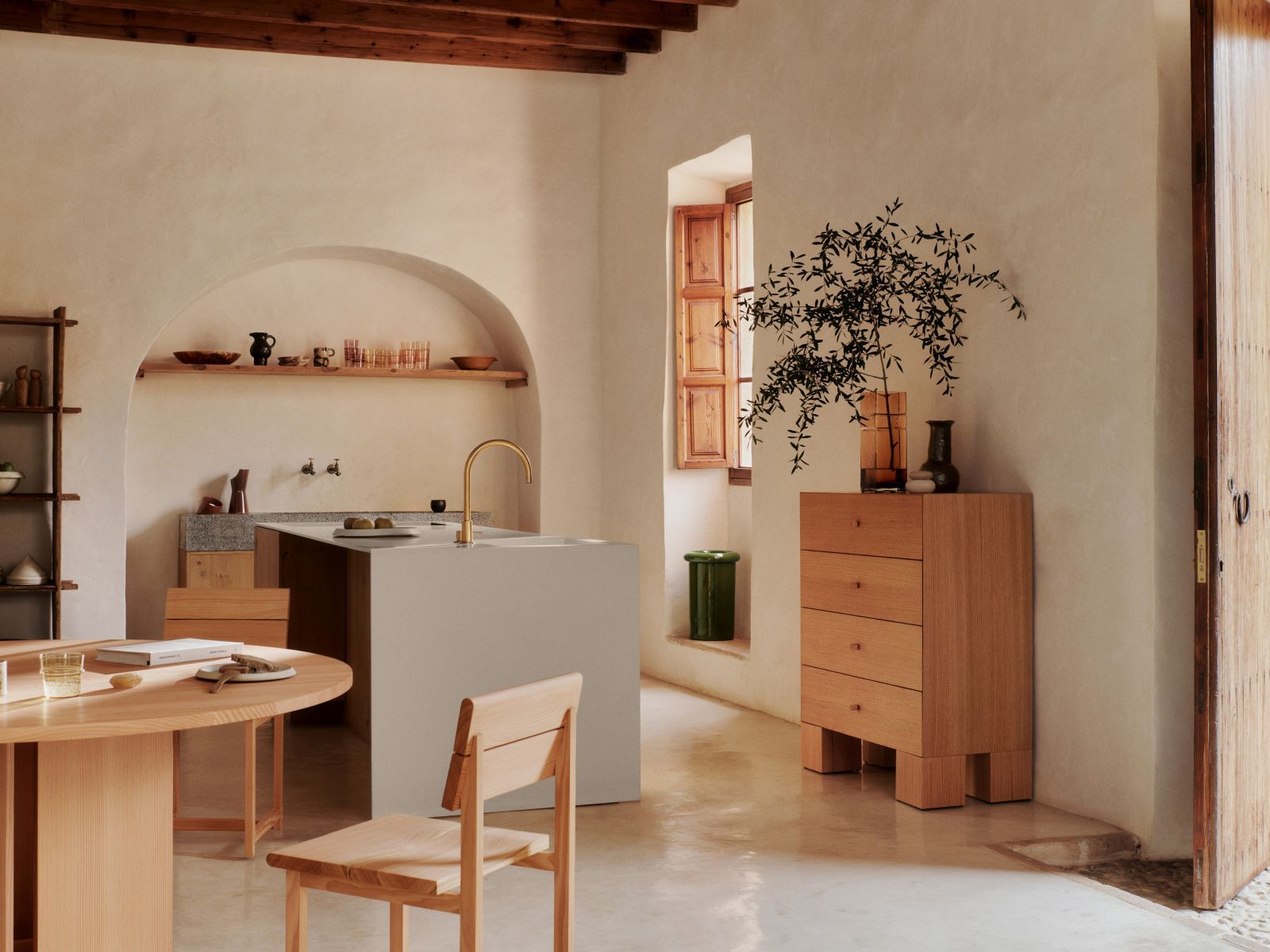 Heller Raum mit rundem Holztisch, Aukko Esstisch von Ferm Living, Stuhl und Kücheninsel.